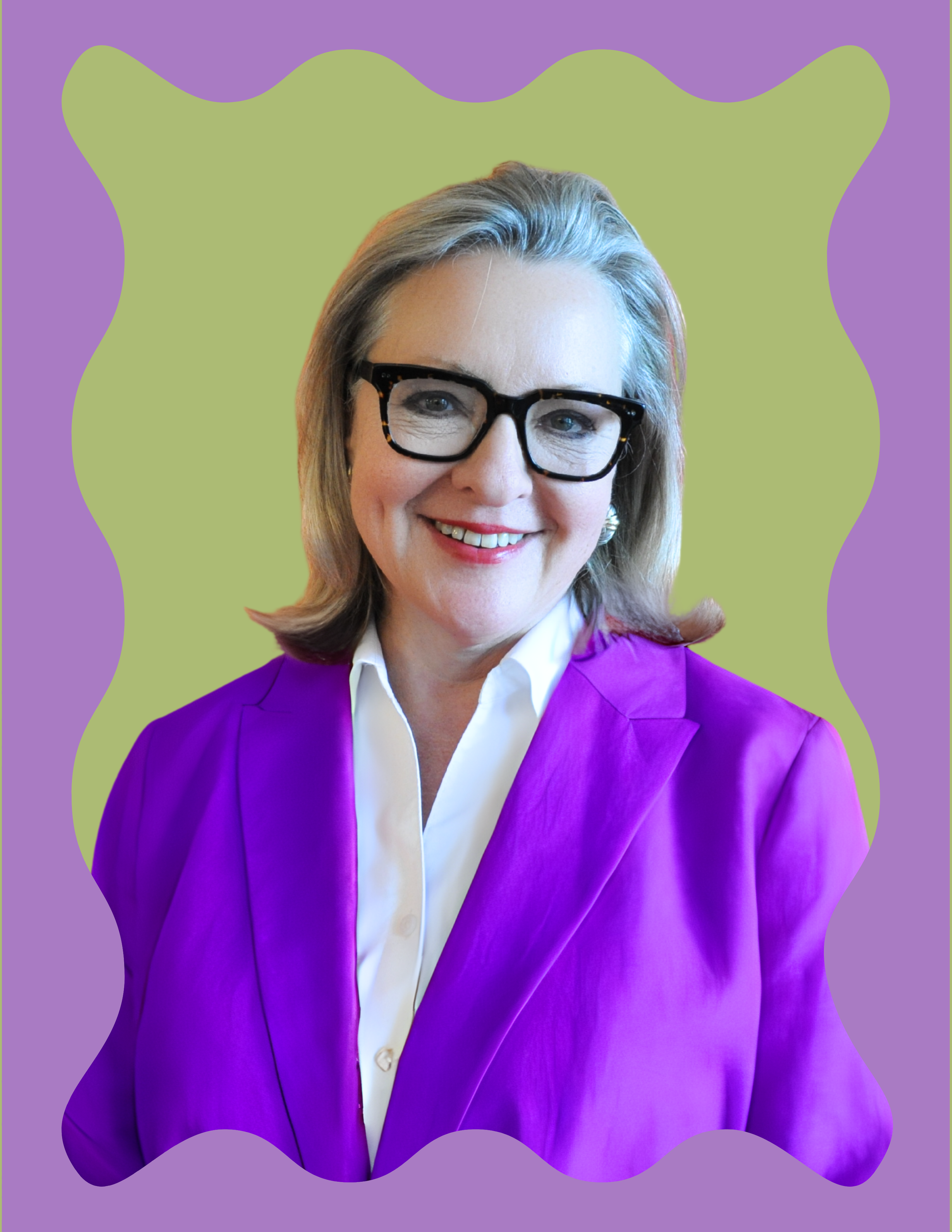 A smiling woman with blonde hair, wearing black-rimmed glasses, a white shirt, and a purple blazer, posed against a decorative background with a green center and purple border.