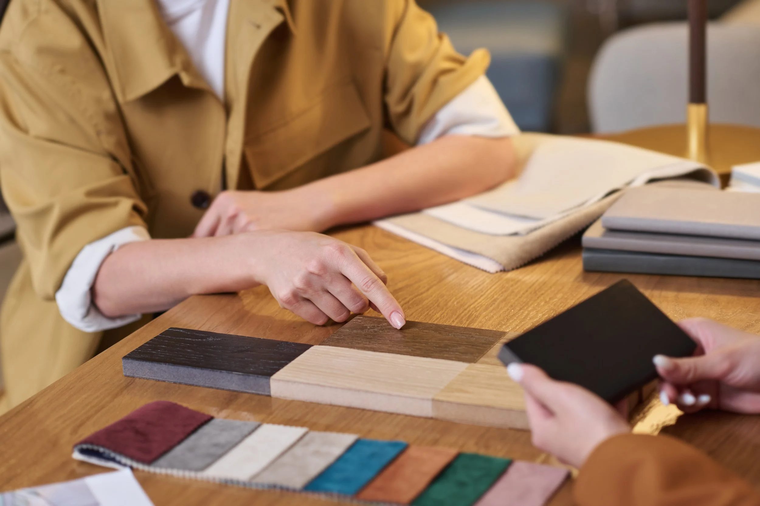 Person showing various wood sample colors to another person at a design consultation.