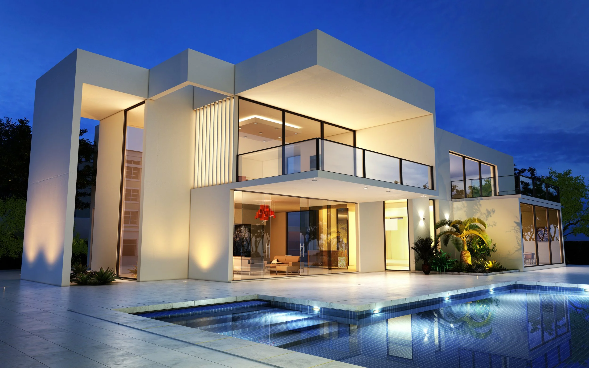 Modern white house with large glass windows and balcony, illuminated at night, with a swimming pool in the foreground, surrounded by plants and trees.