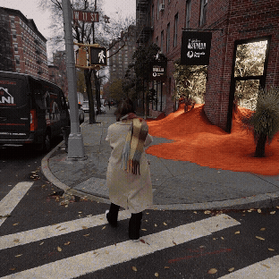 Person walking on a crosswalk near a building with orange spray foam insulation.