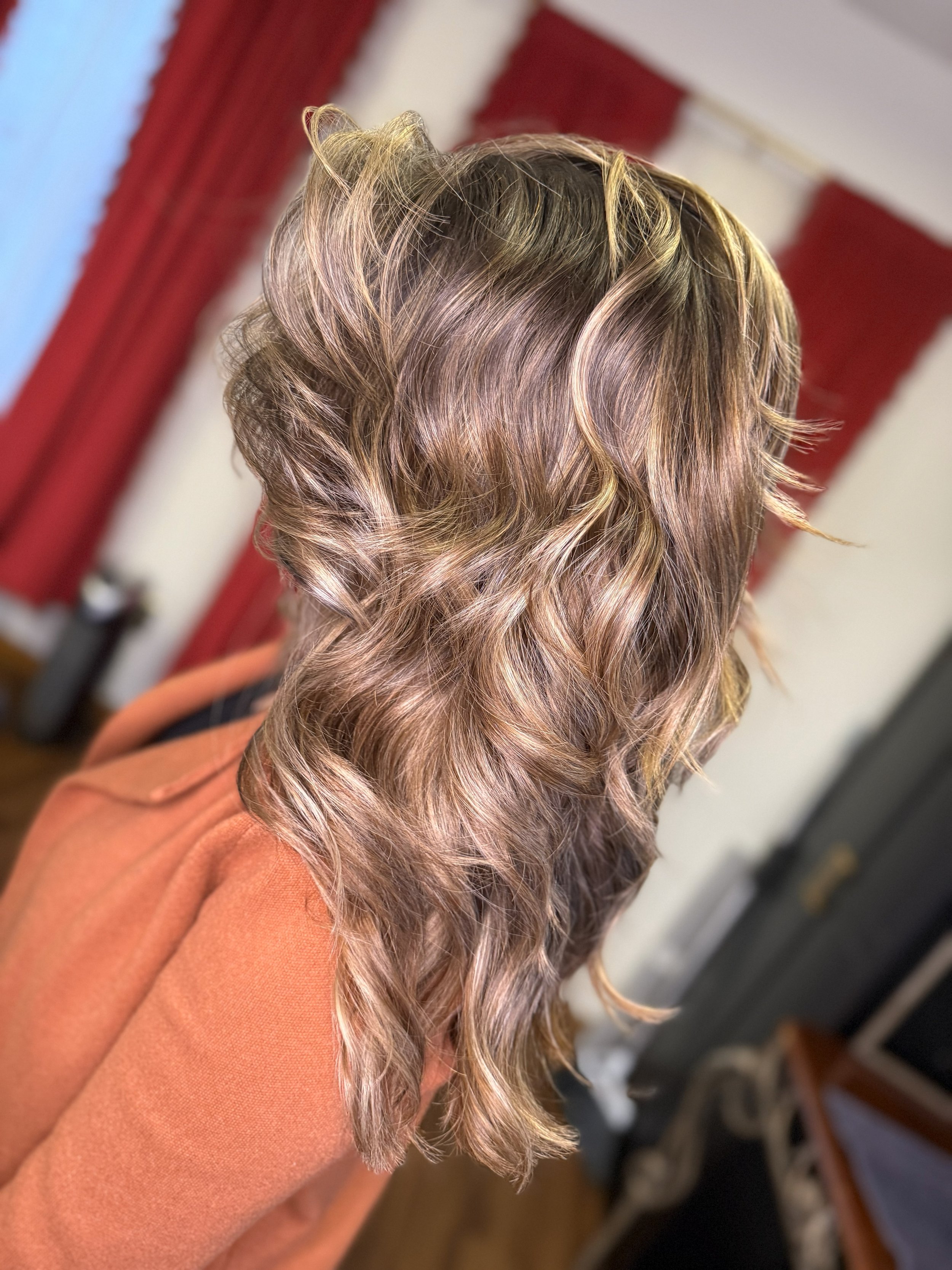 Wavy, highlighted blonde hair styled in loose curls, seen from the back.