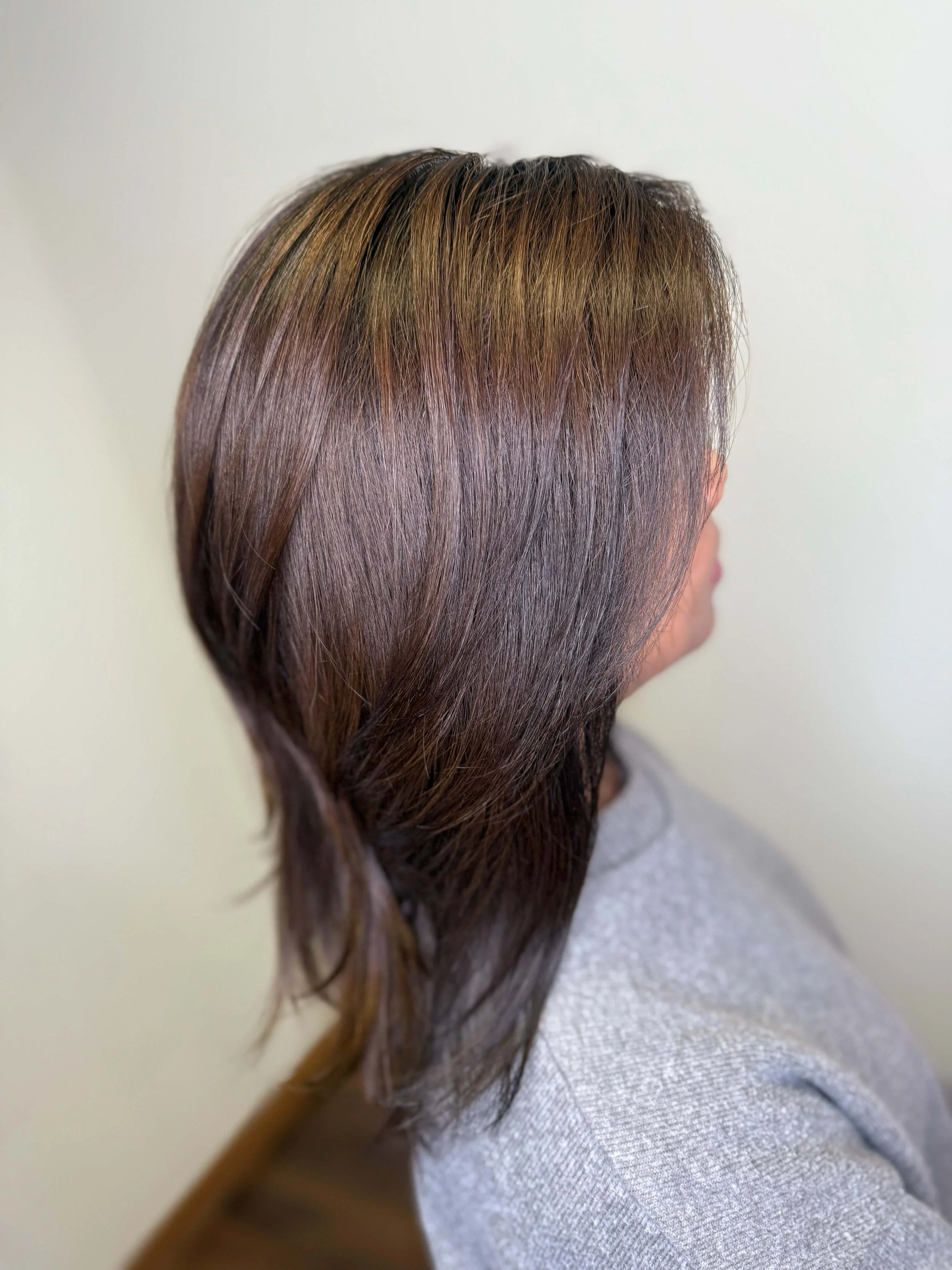 Side view of a woman's layered brown hair with subtle highlights.