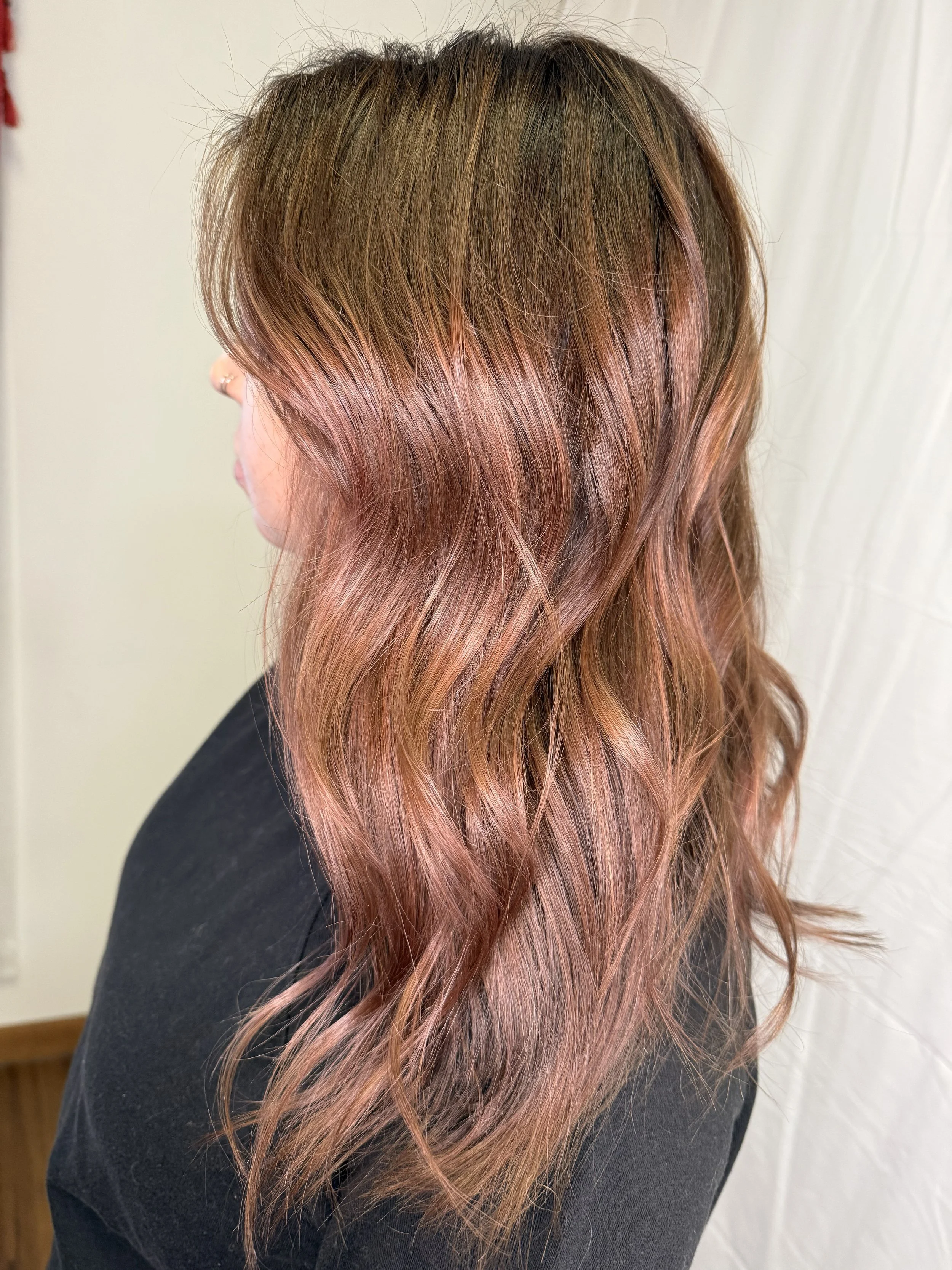 Woman with wavy, shoulder-length hair dyed in shades of pink and brown.