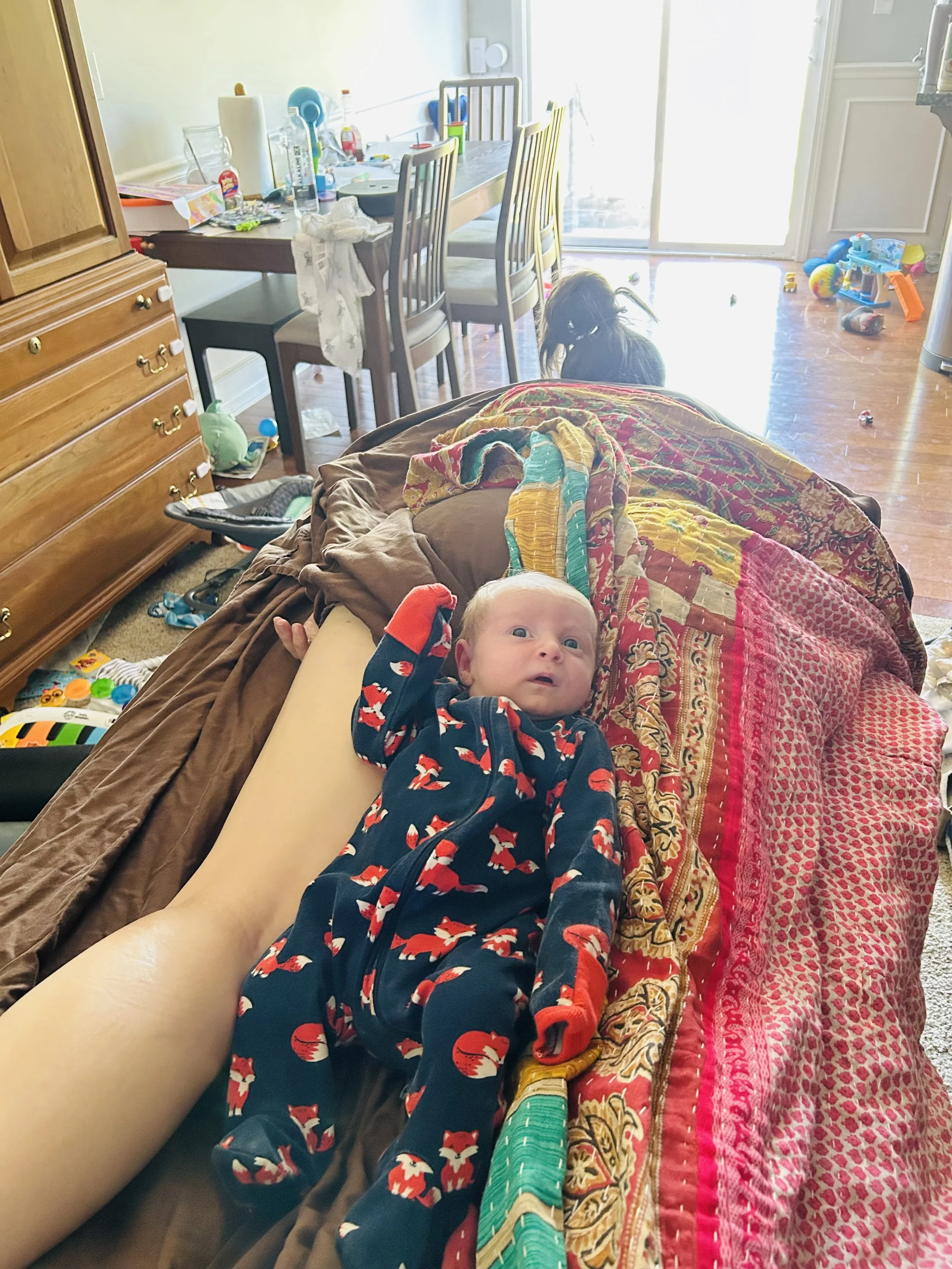 Mother receiving postpartum bodywork while resting with her baby