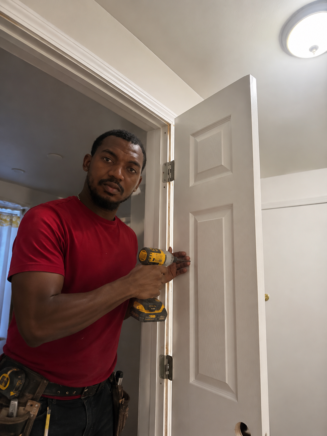 Man installing a door with a cordless drill in a home interior.