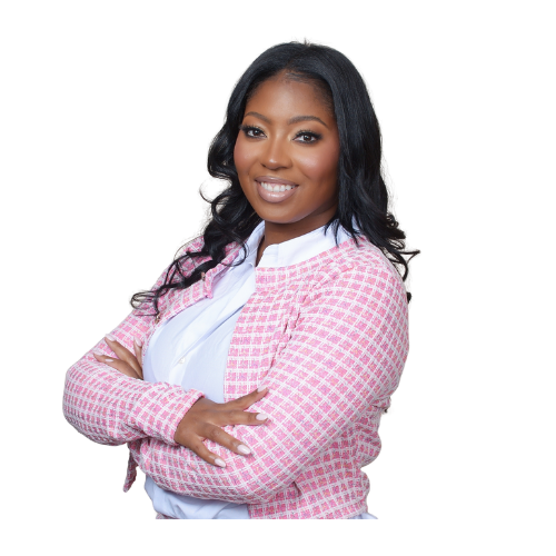 A confident woman with long black hair, wearing a pink checkered blazer over a white shirt, smiling with arms crossed.