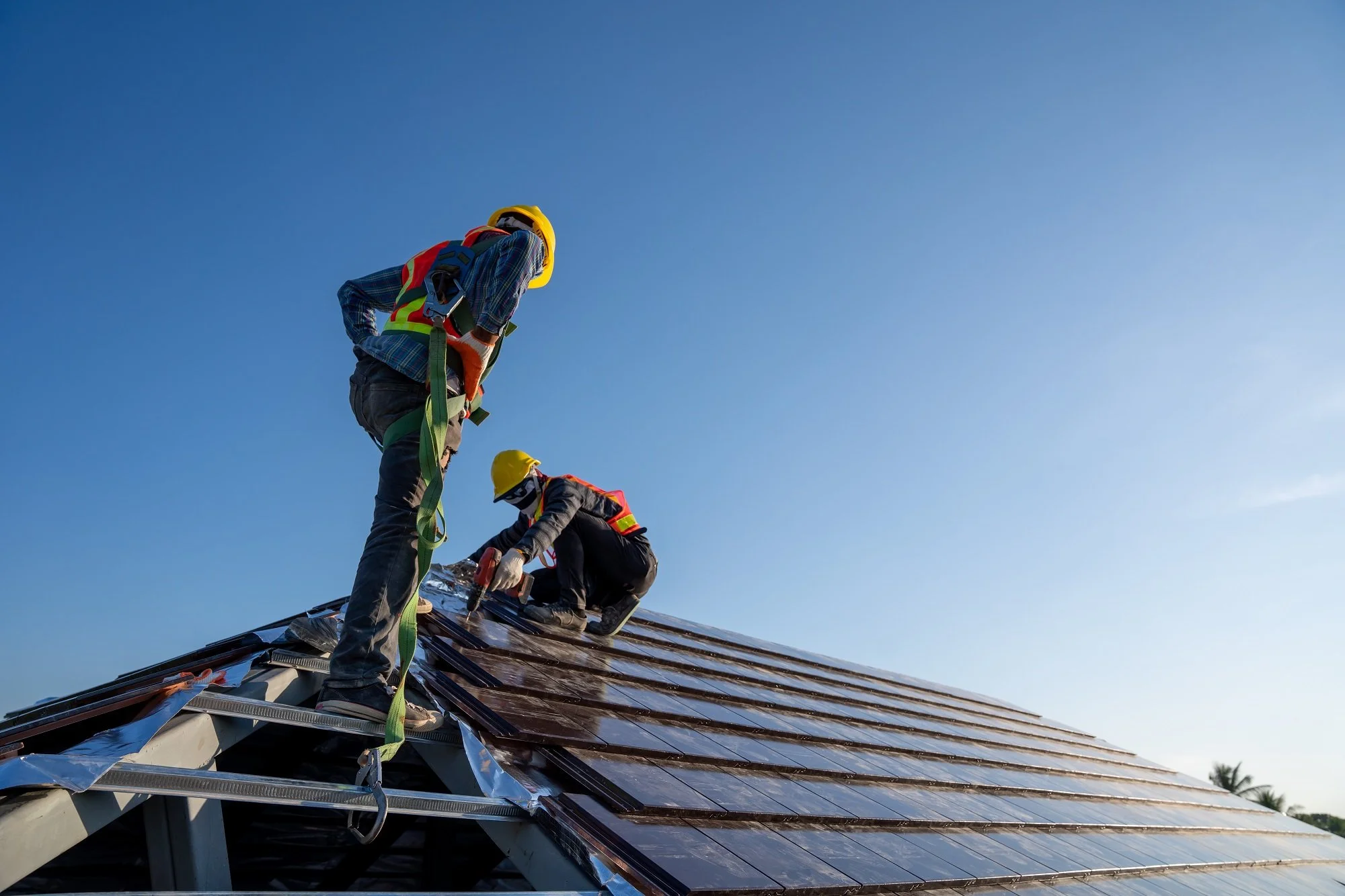 Professional roofing contractors installing a standing seam metal roof on a home in North Vancouver, British Columbia