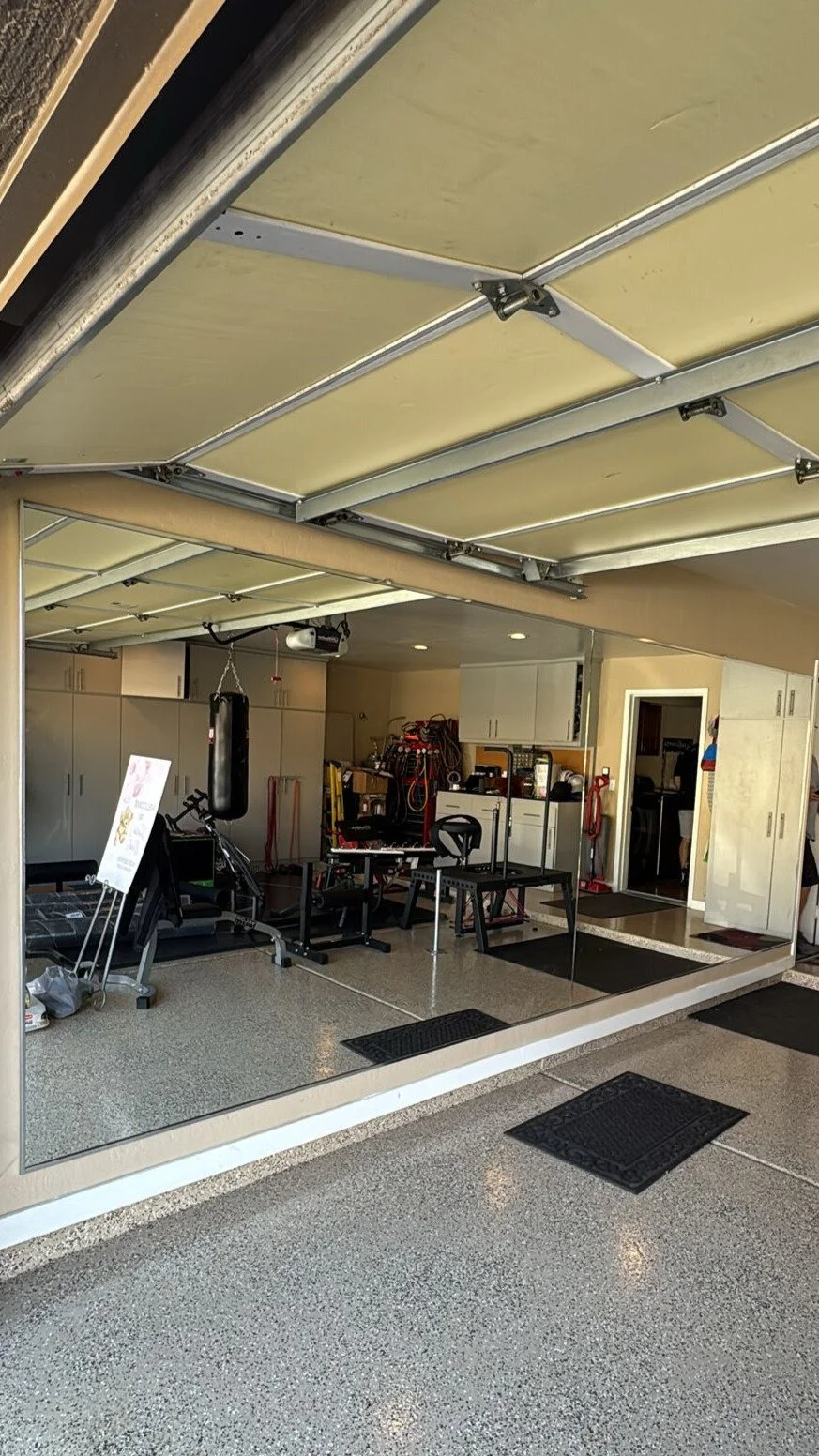 Indoor garage gym with workout equipment, boxing punching bag, and storage cabinets.
