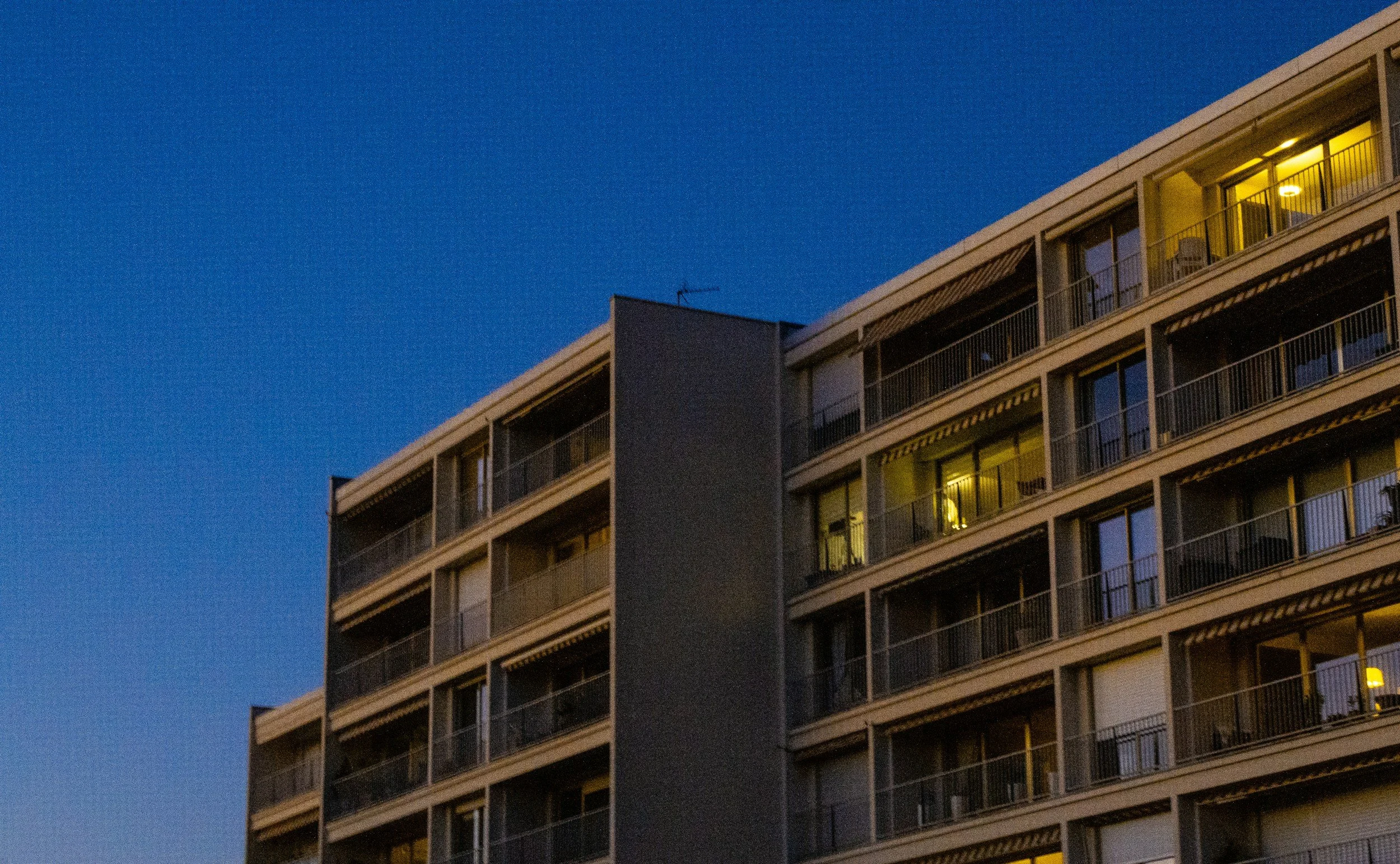 Apartment building during dusk with some lit windows.
