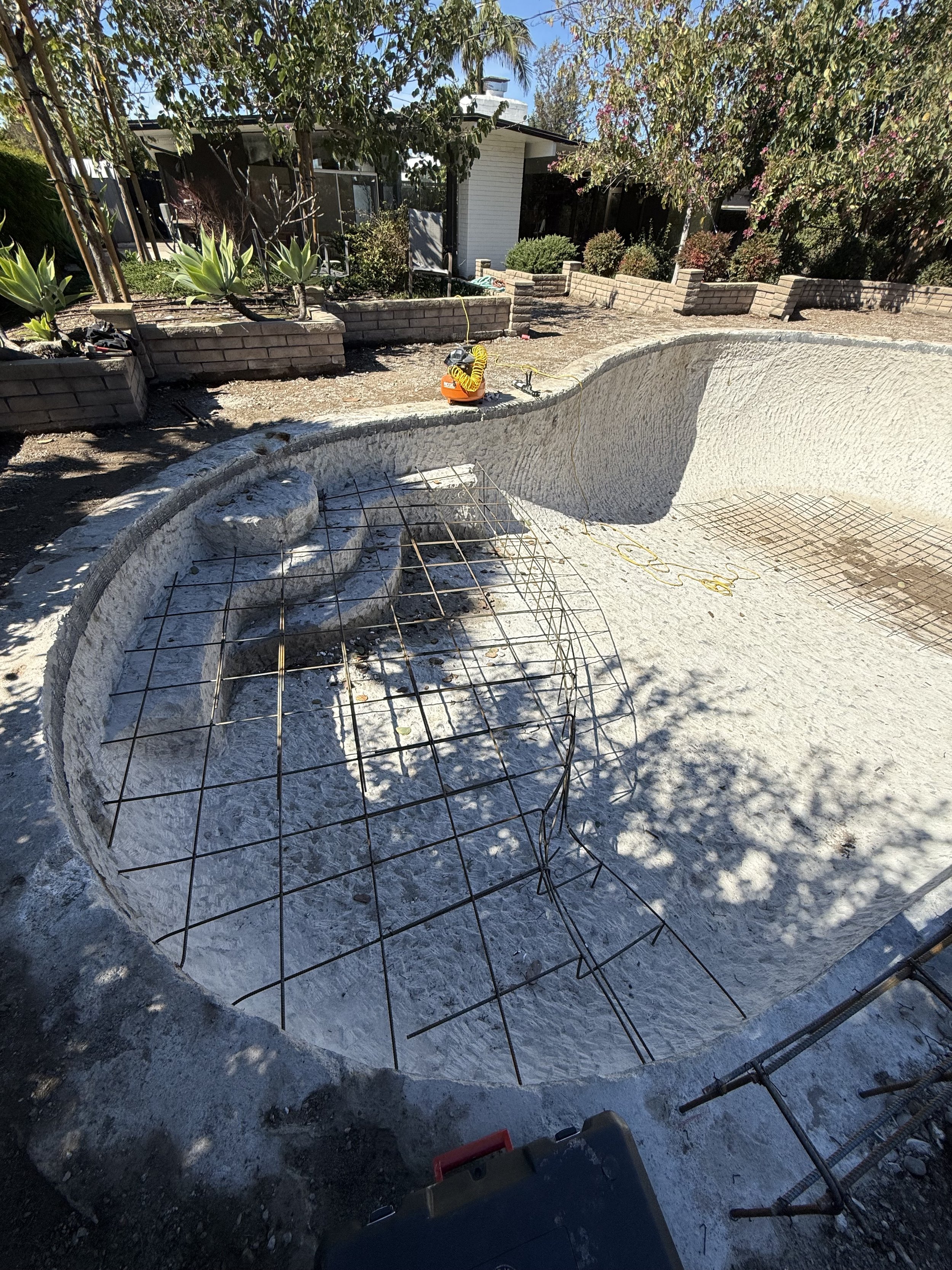 Empty swimming pool under construction with metal rebar framework set in the concrete.