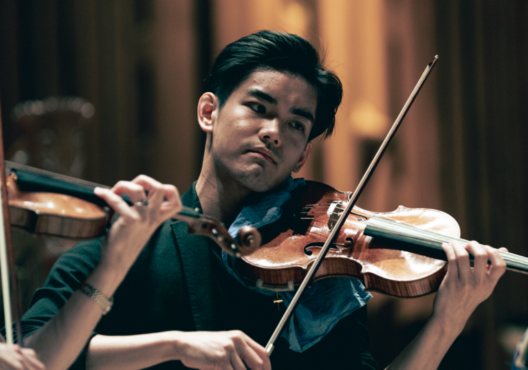 Young man playing the violin in a performance setting.