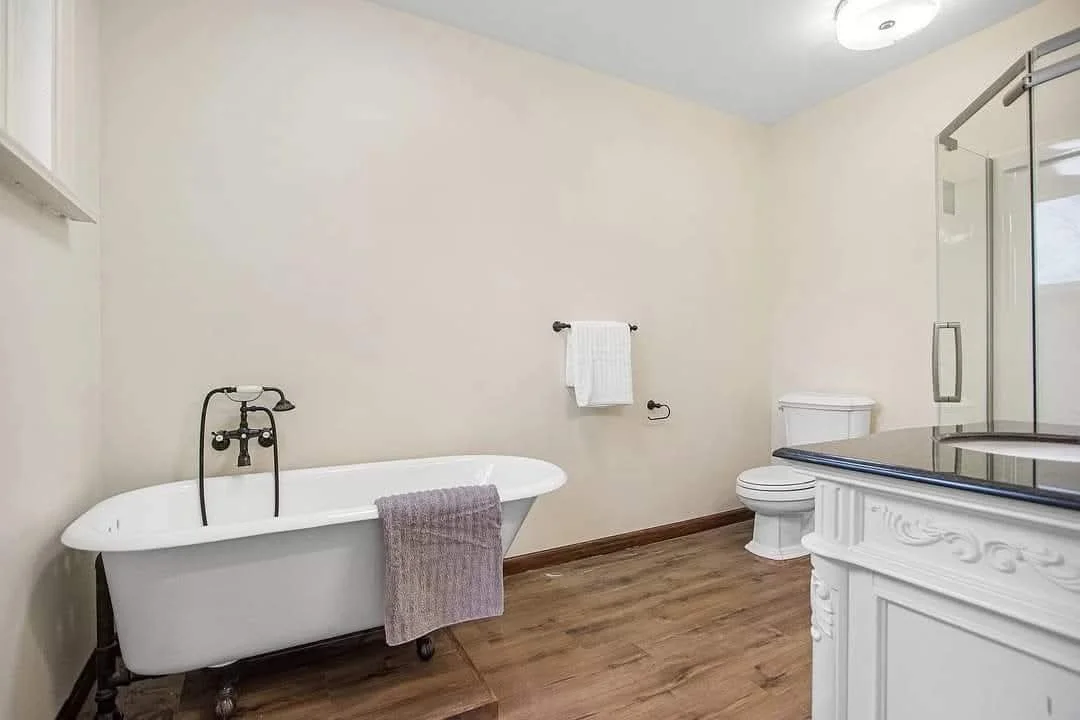 Bathroom with a clawfoot bathtub, toilet, glass shower enclosure, and wooden floor - high end finishes.