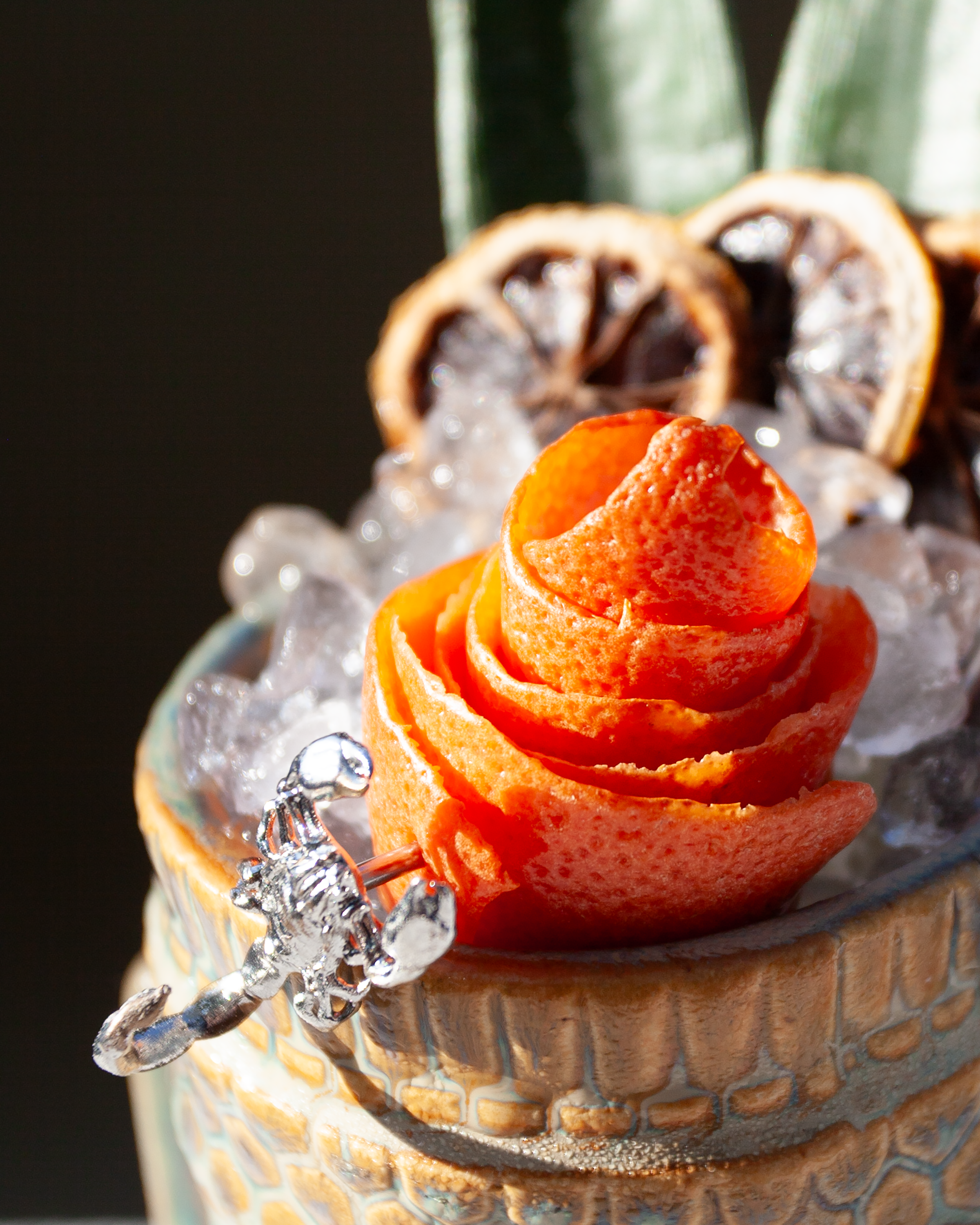 Close-up of an orange rose in a decorative vase with sparkling crystal accents.