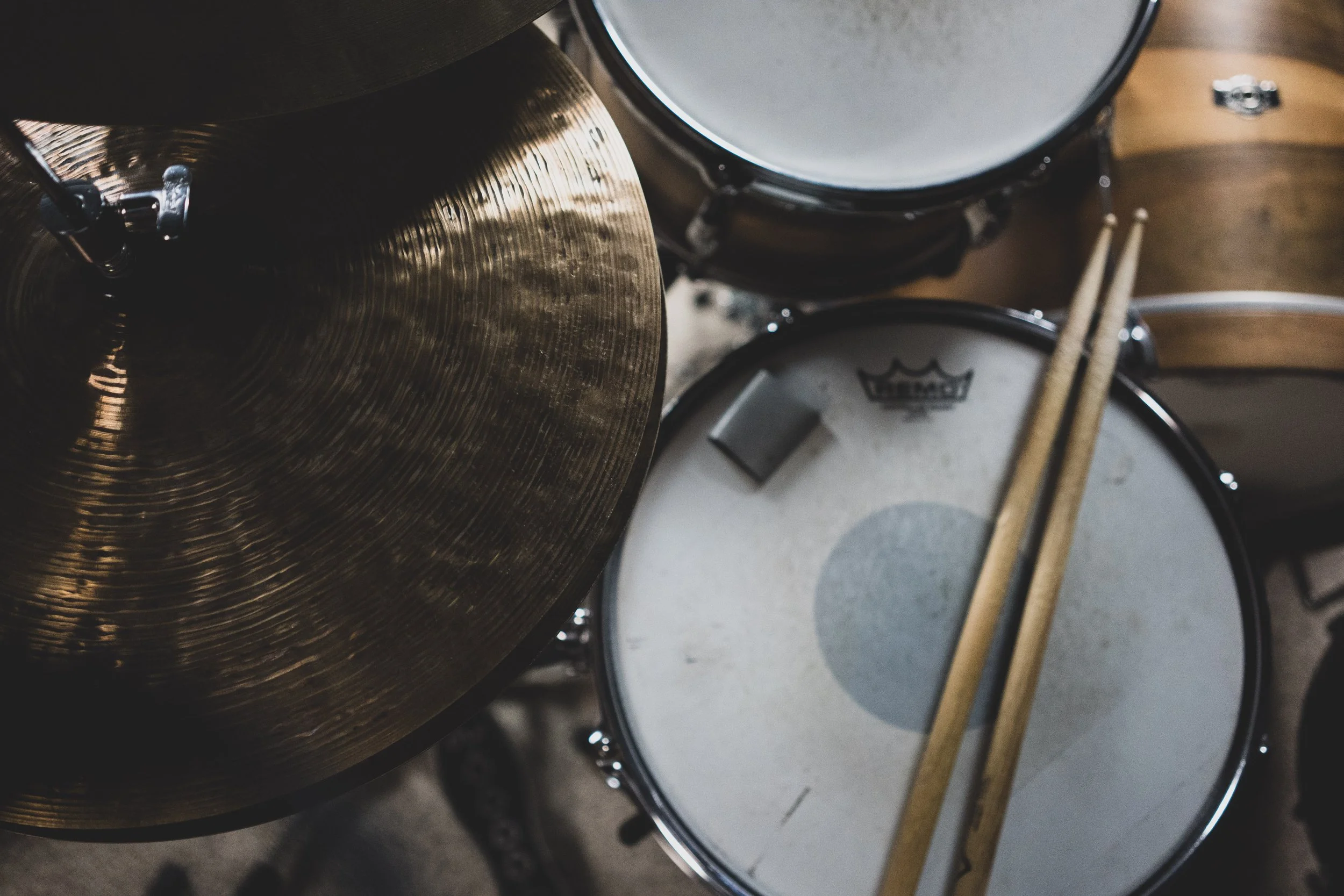 Overhead view of a drum set with a cymbal, snare drum, and drumsticks resting on the snare drum.