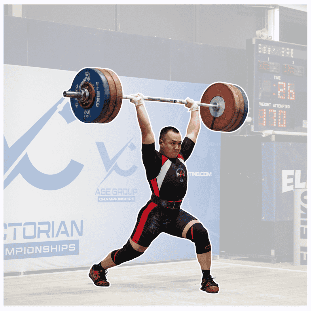 Male weightlifter in black and red uniform lifting a barbell overhead during competition.