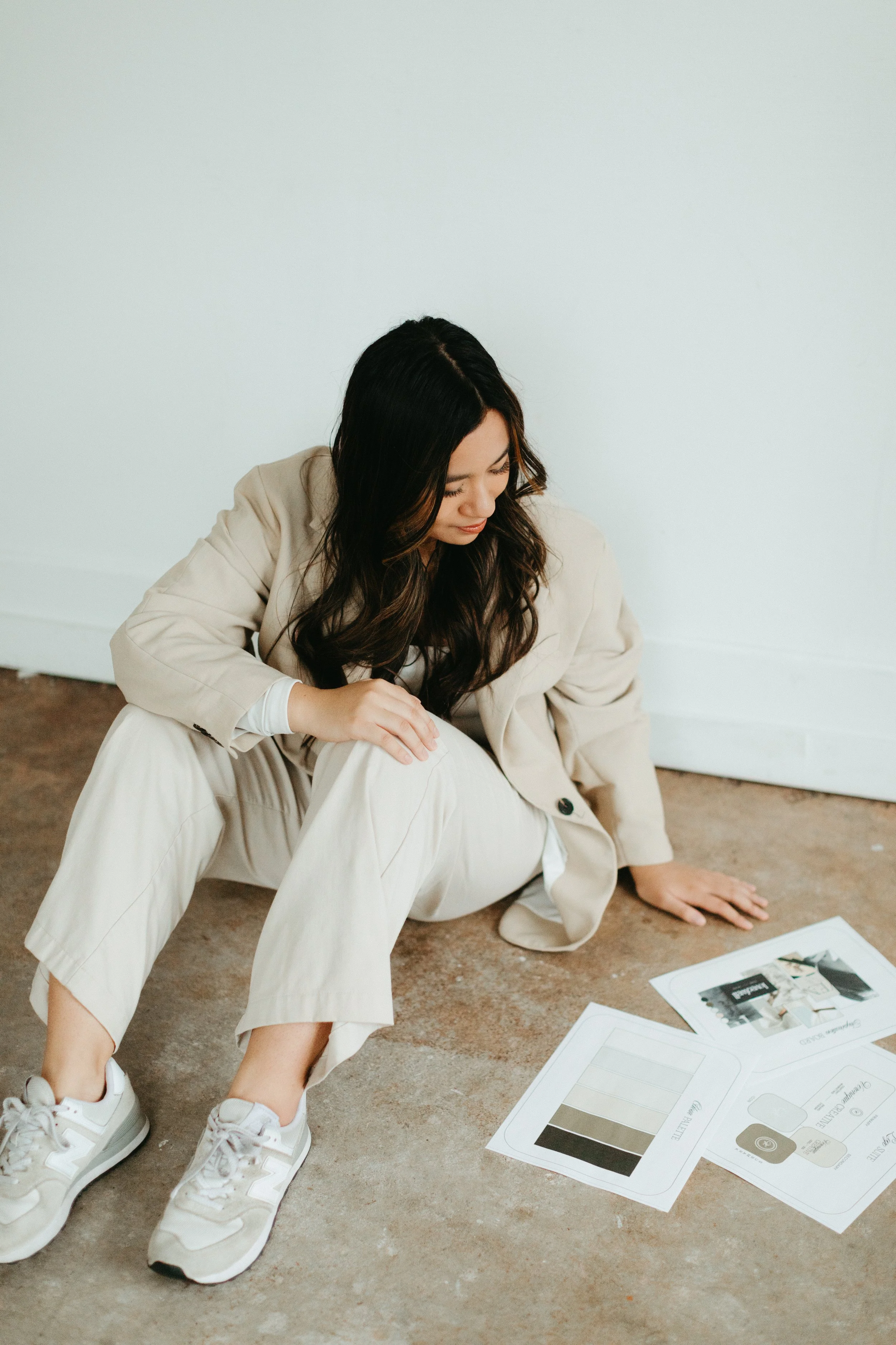 A woman sitting on the floor reviewing interior design samples and color swatches.