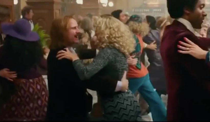 People dancing closely together in a lively social setting, possibly a dance hall or party.