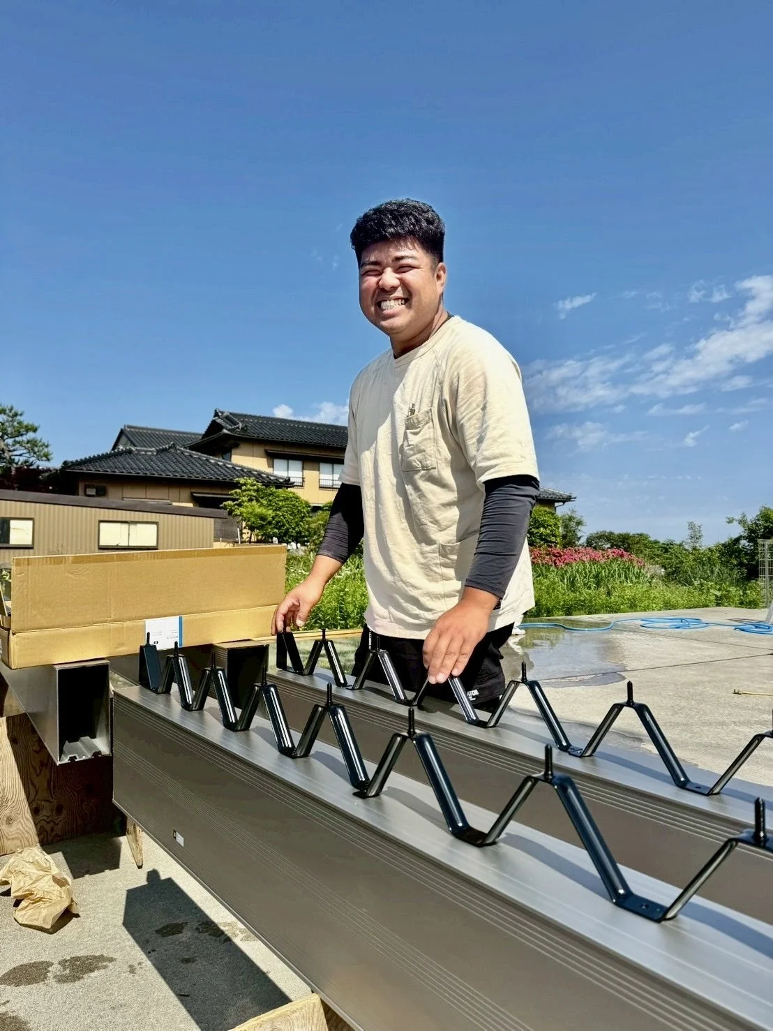 笑顔の社長。背景は青空と家の屋根。