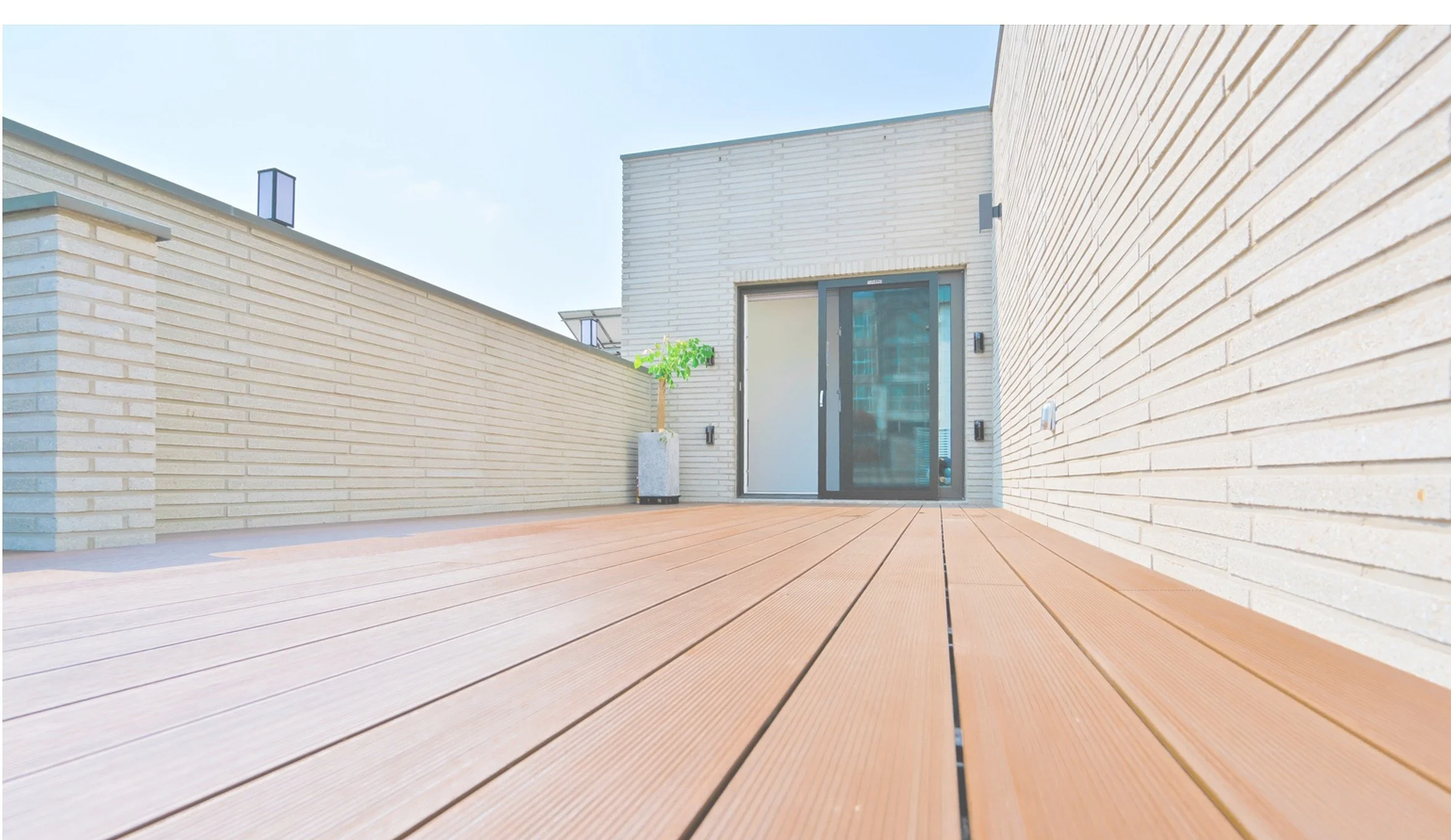 テラスから見た屋外の木製デッキ。晴れた日で明るい照明の屋外空間。