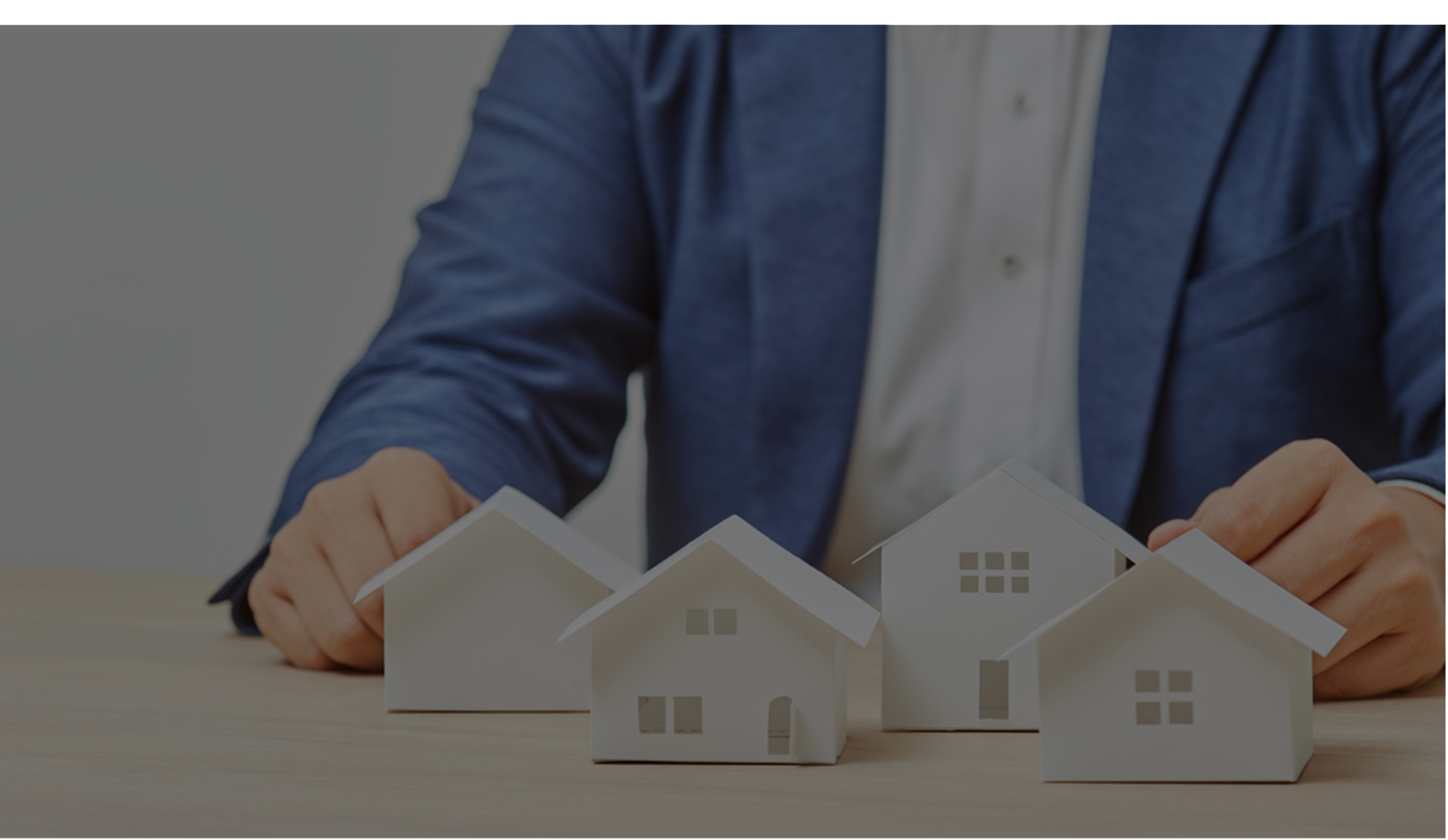 ハウスメーカーの男性が小さな白い住宅模型をテーブル上に並べている