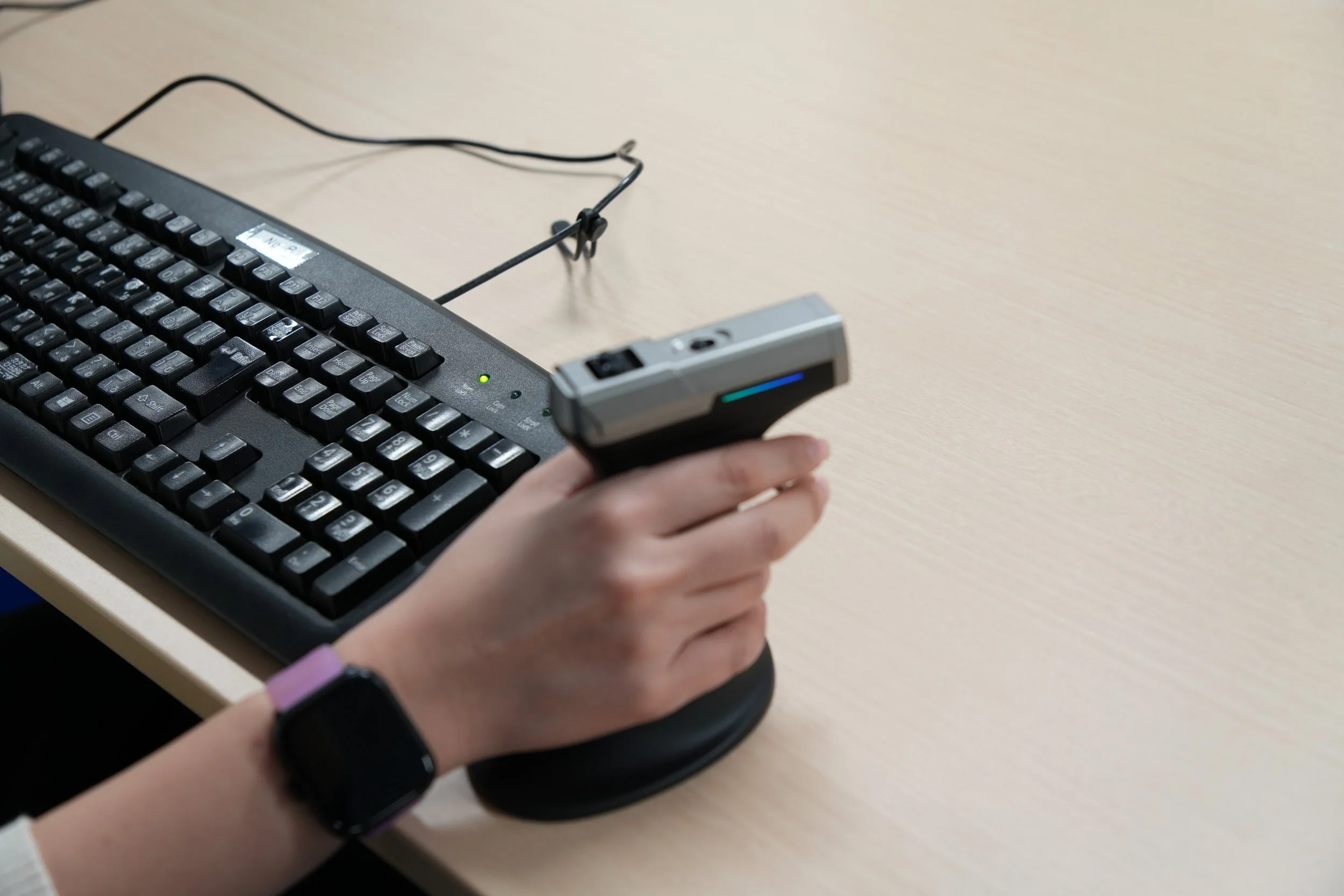キーボードと手に持った電子機器を操作している様子が写っている画像