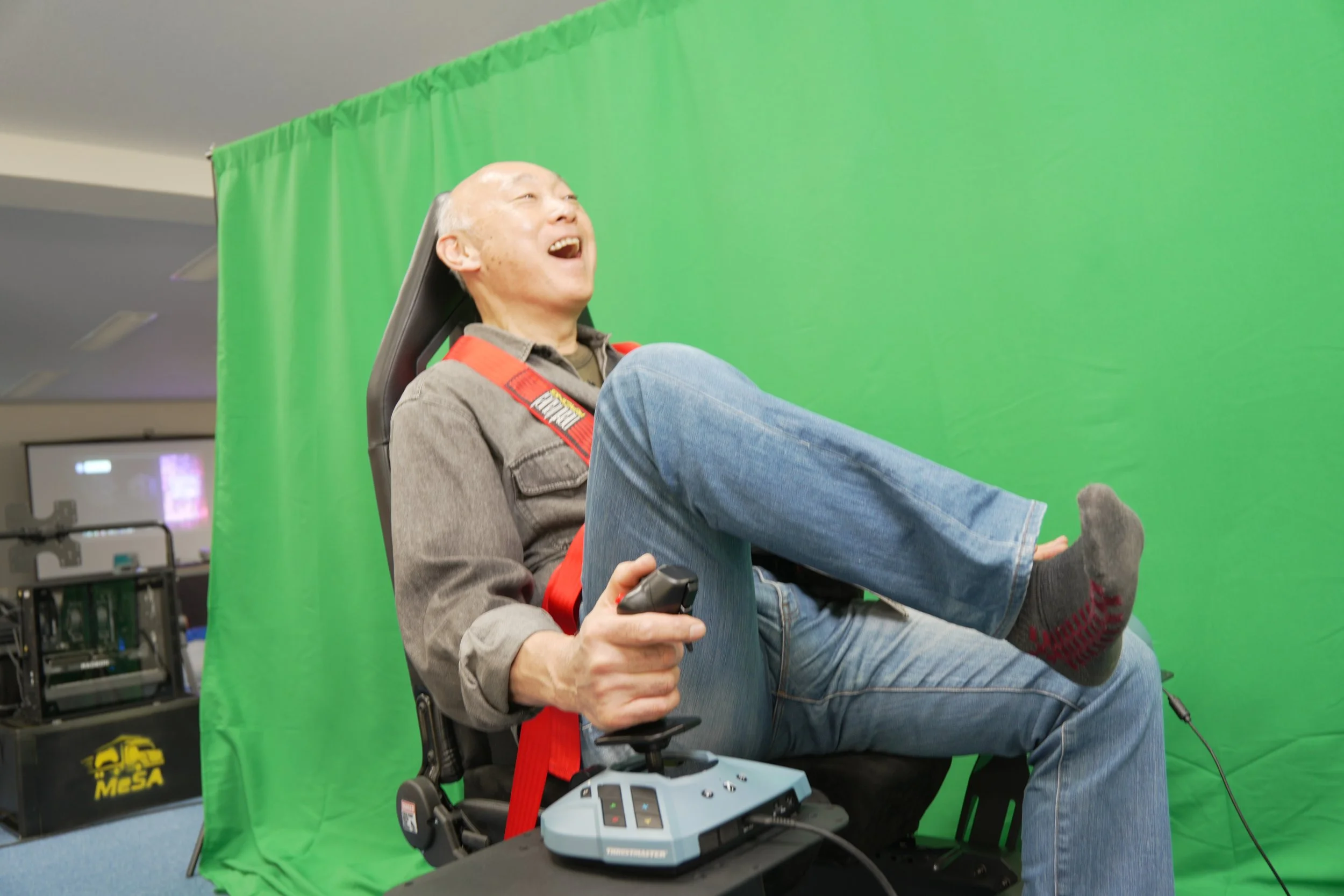 緑の背景スクリーンの前で、楽しそうにゲームを操作している老人の男性。