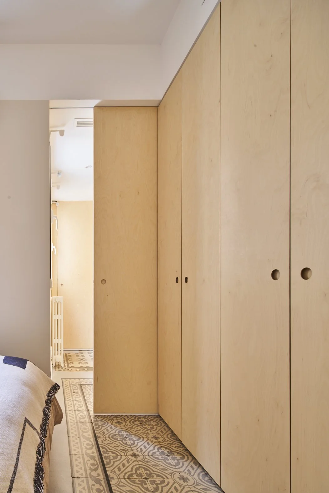 Armario de madera con puertas redondas en un interior con azulejos decorativos en el suelo.