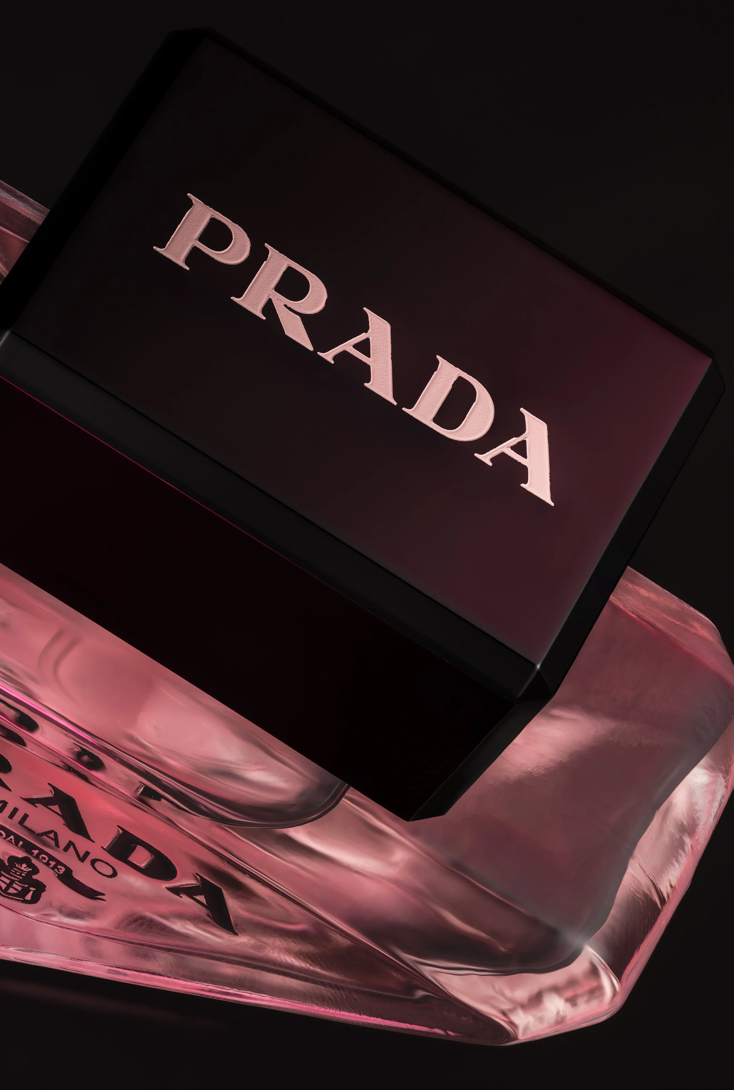 Luxury perfume bottle photographed with dramatic red lighting and reflective shadows.