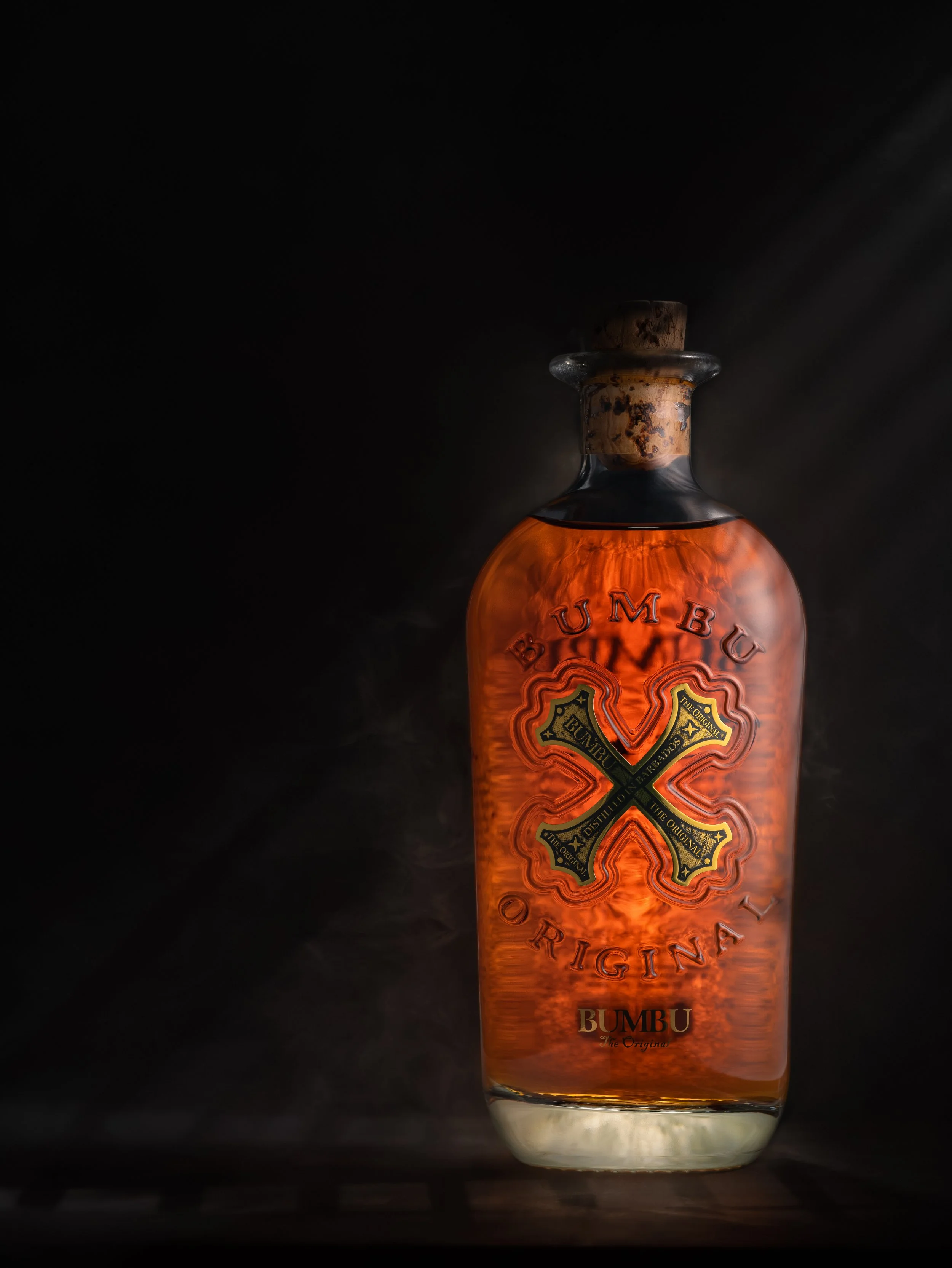 Whiskey bottle photographed with warm highlights and atmospheric shadows against a dark background.