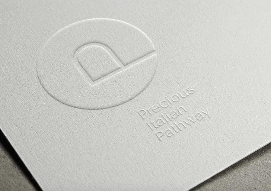 Logo in rilievo su carta bianca: 'Precious Italian Pathway' con un logo circolare contenente una lettera 'P' stilizzata.
