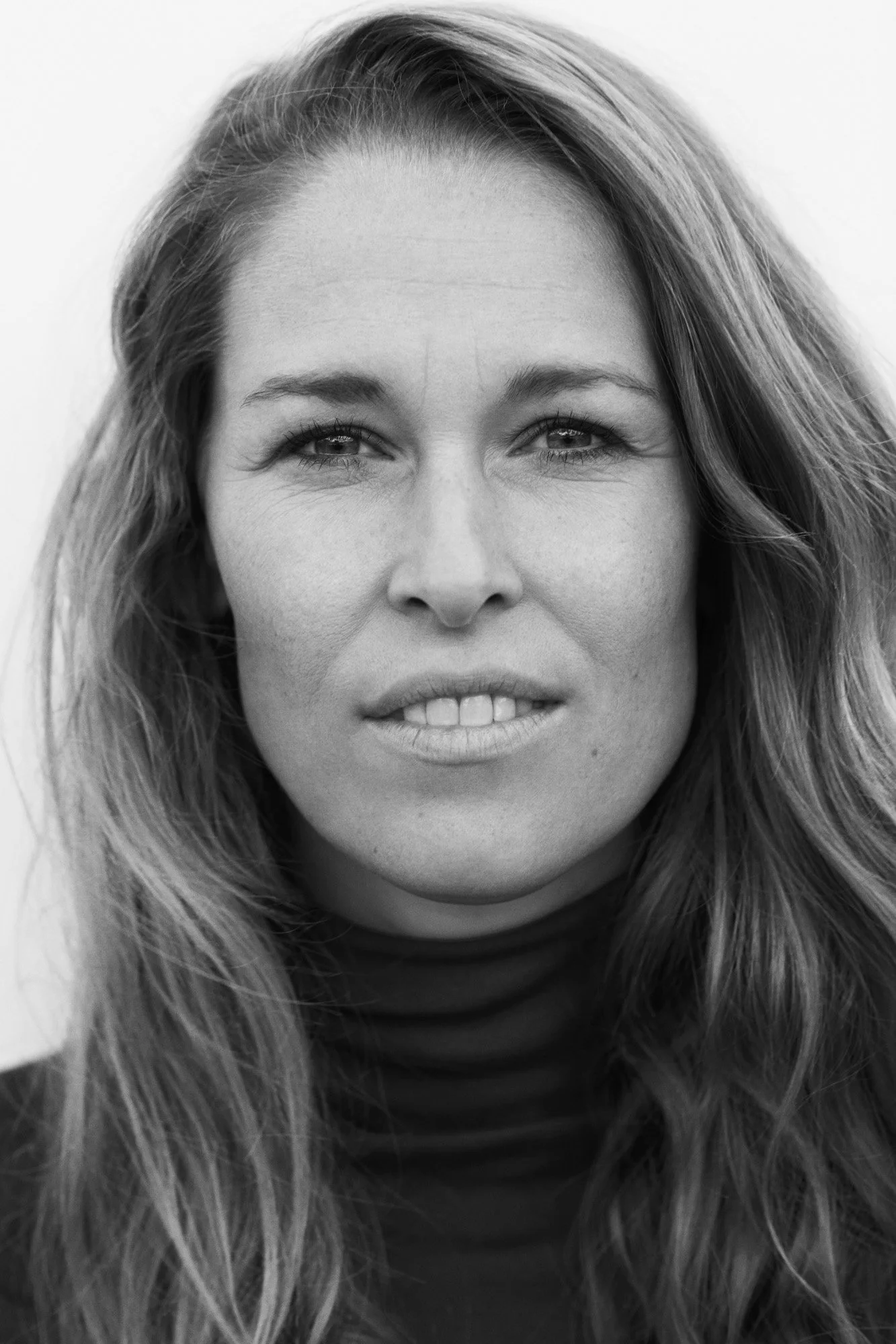 Portrait Lea Korsgaard Zetland - Black and white close-up portrait of a woman with long wavy hair, looking directly at the camera with a neutral expression.