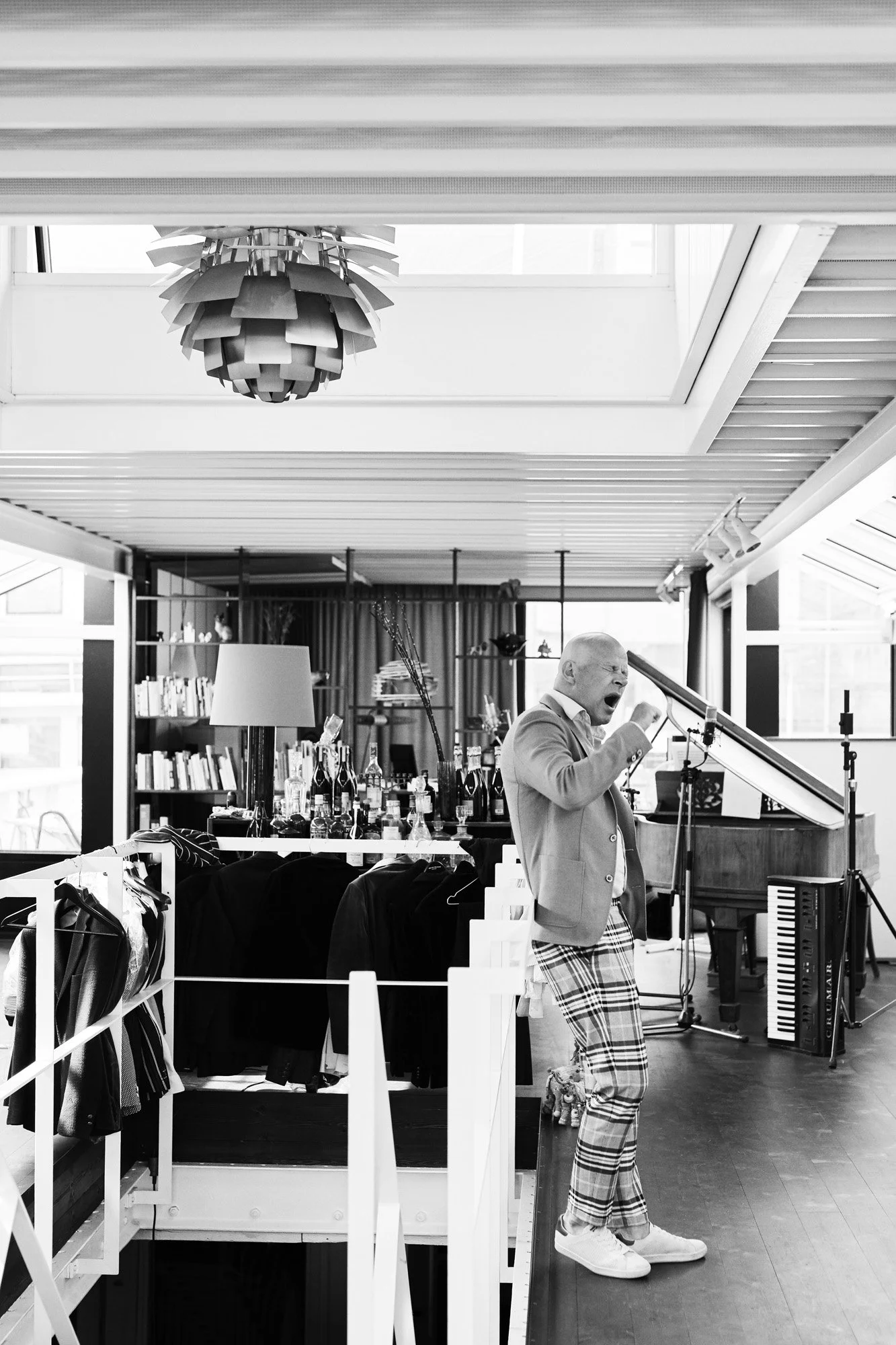 Thomas Blachman - Retorik Magasinet - A man singing into a microphone in a room with a grand piano, a bookshelf, and various decorative items.