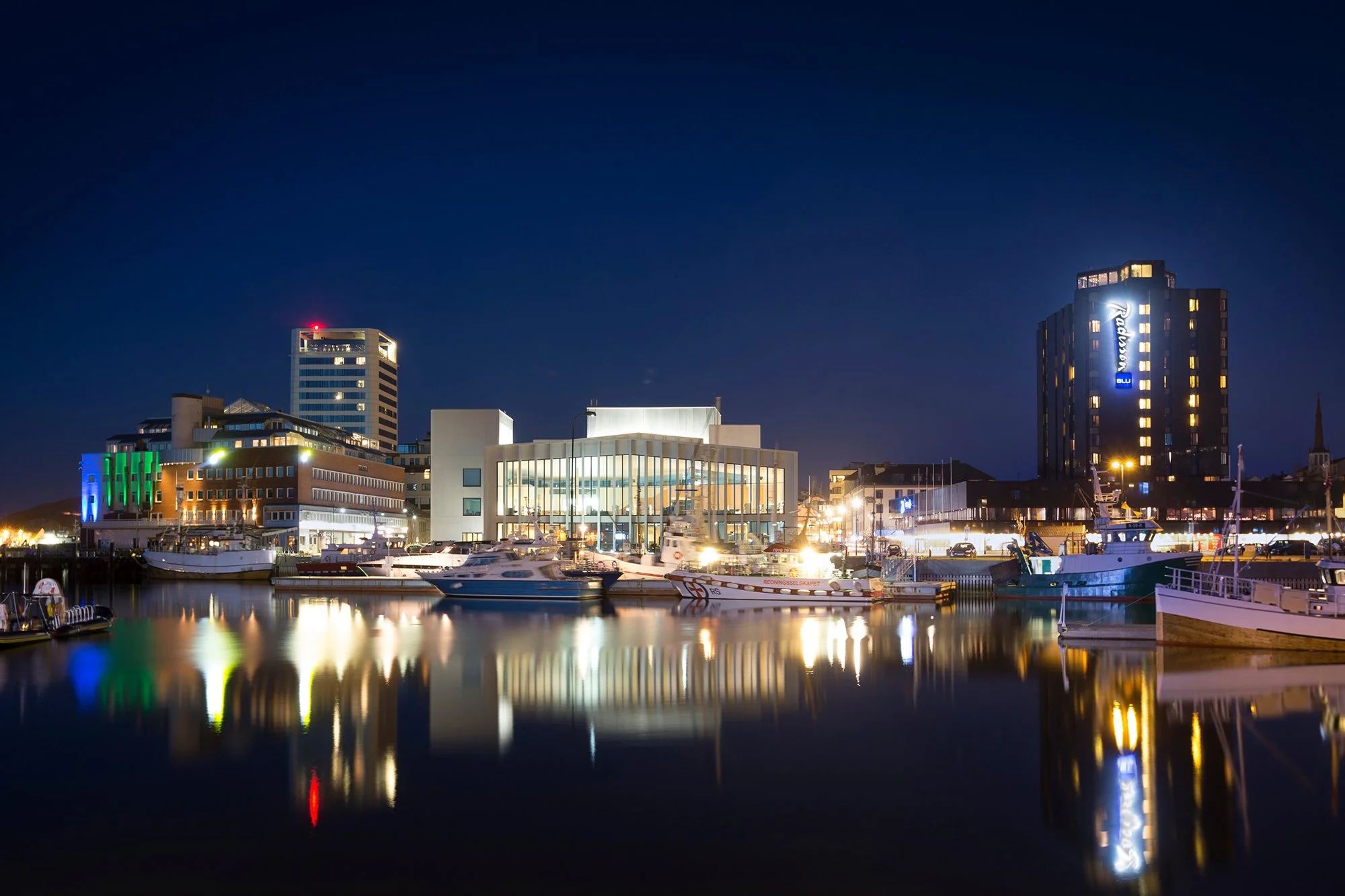 Sea with illuminated buildings in the background at night
