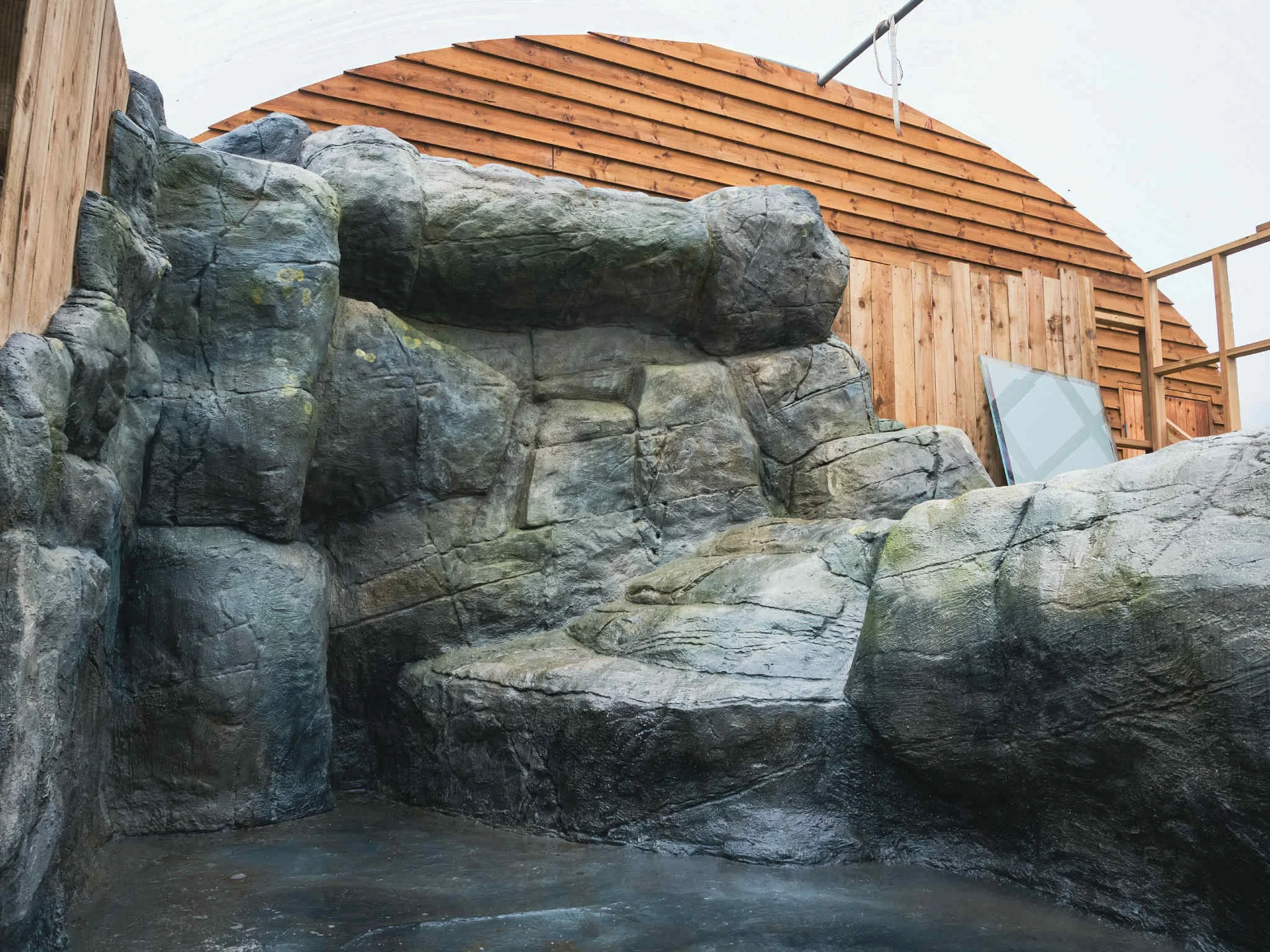 Artificial rock climbing wall with a wooden structure in the background.