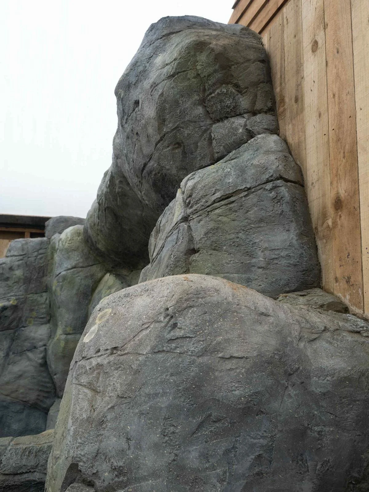 Large stacked rocks placed against a wooden wall inside a building.