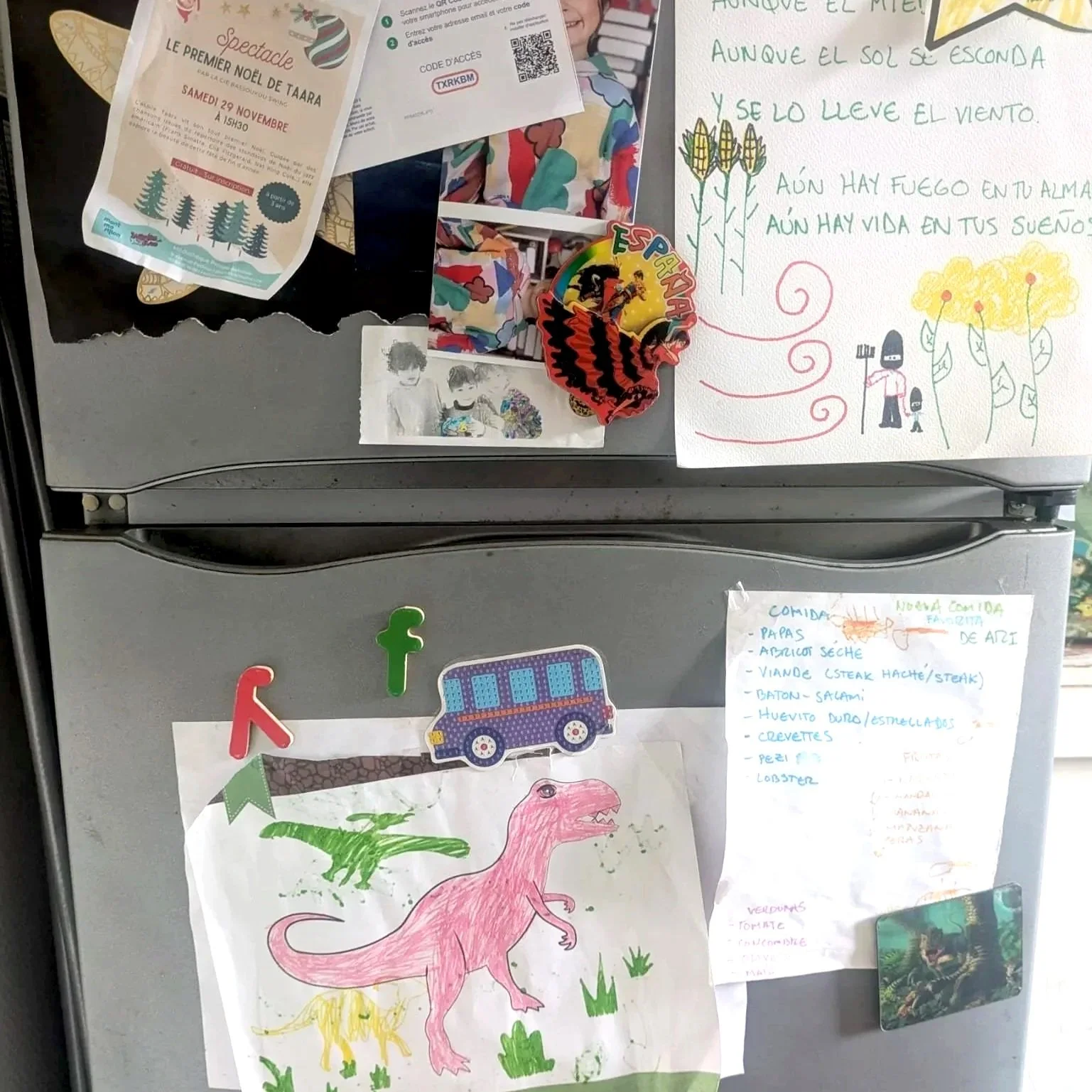 A refrigerator door covered with various colorful drawings, handwritten notes, and small decorative items. The drawings include a pink dinosaur, a green dinosaur, and a yellow creature, along with a small model of a blue bus. There are notes with lis