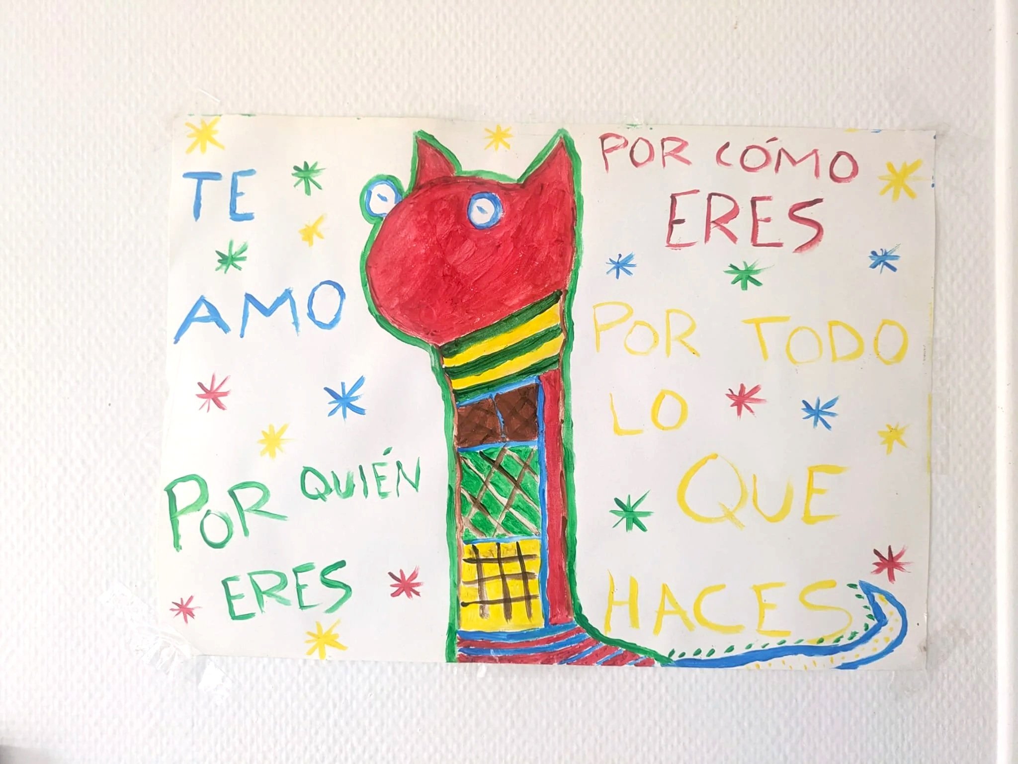 Colorful hand-drawn poster with a cartoon dinosaur and the quote, 'Te amo por quién eres, por todo lo que haces,' surrounded by multicolored stars.