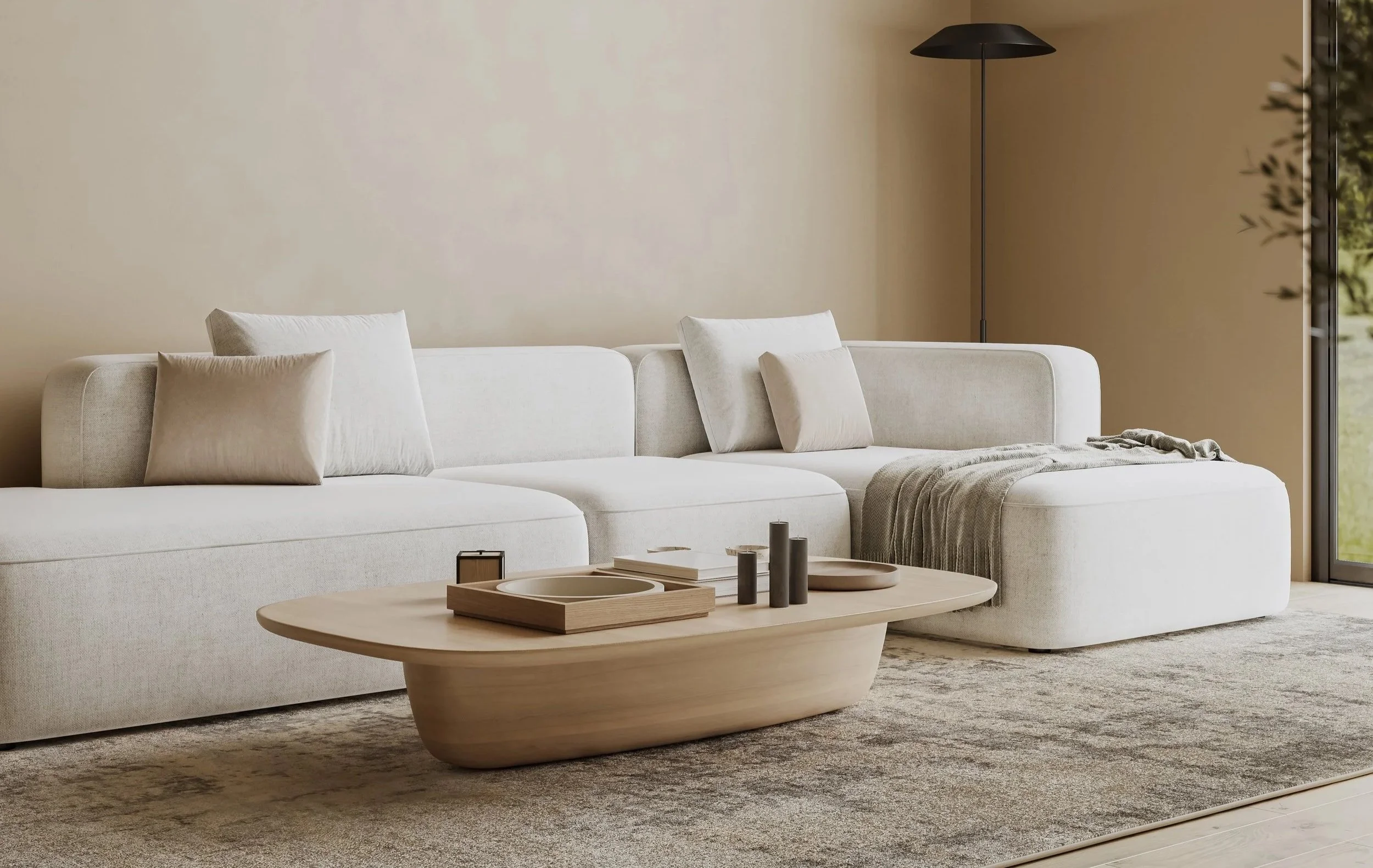 Living room with a white sectional sofa, beige pillows, a wooden coffee table with decorative items, a beige throw blanket, a tall black floor lamp, and a large window with a view of greenery.
