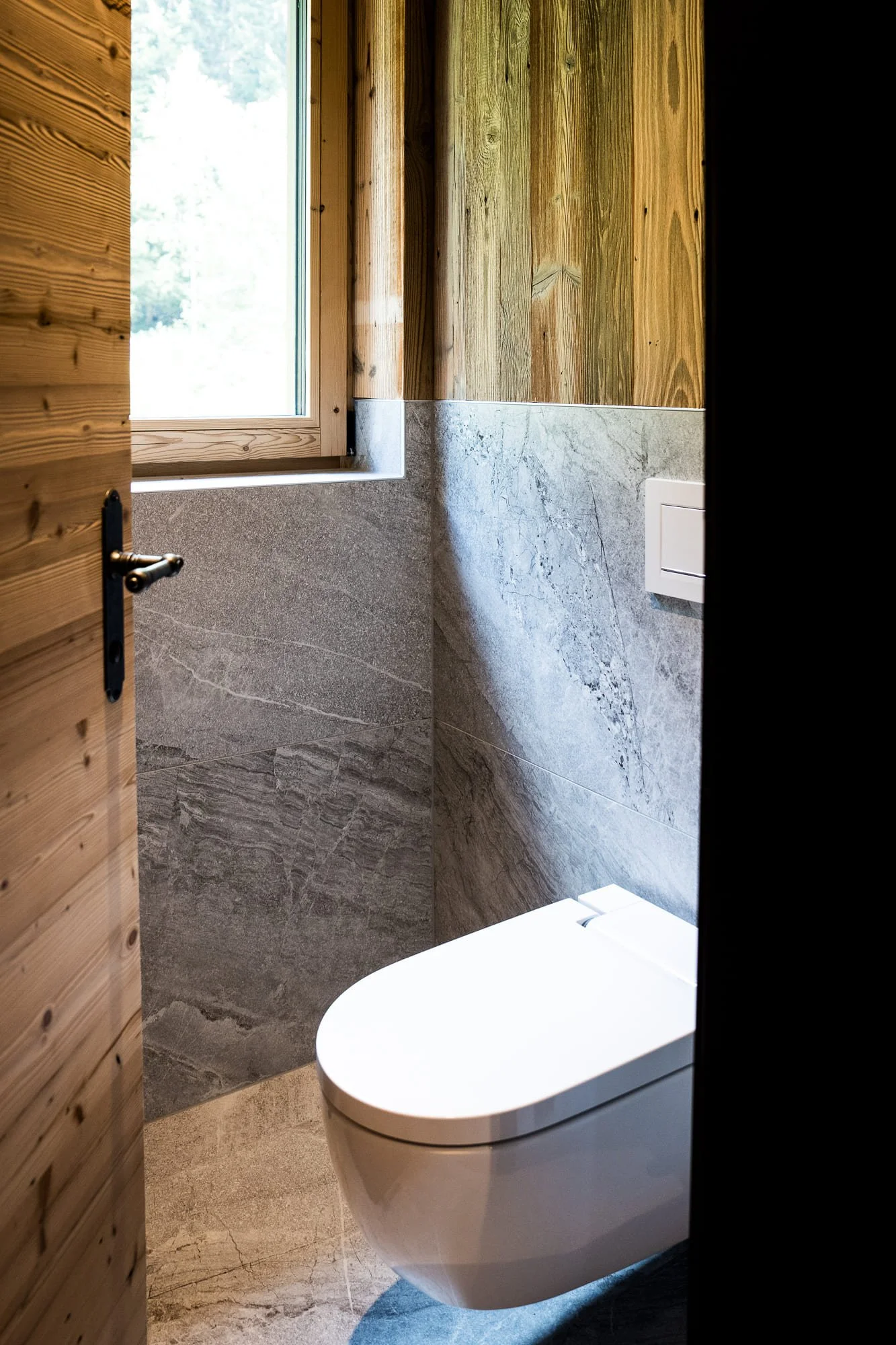 Ein Badezimmer mit Holzwänden, einem großen spiegel und einer modernen Waschbeckenanlage.