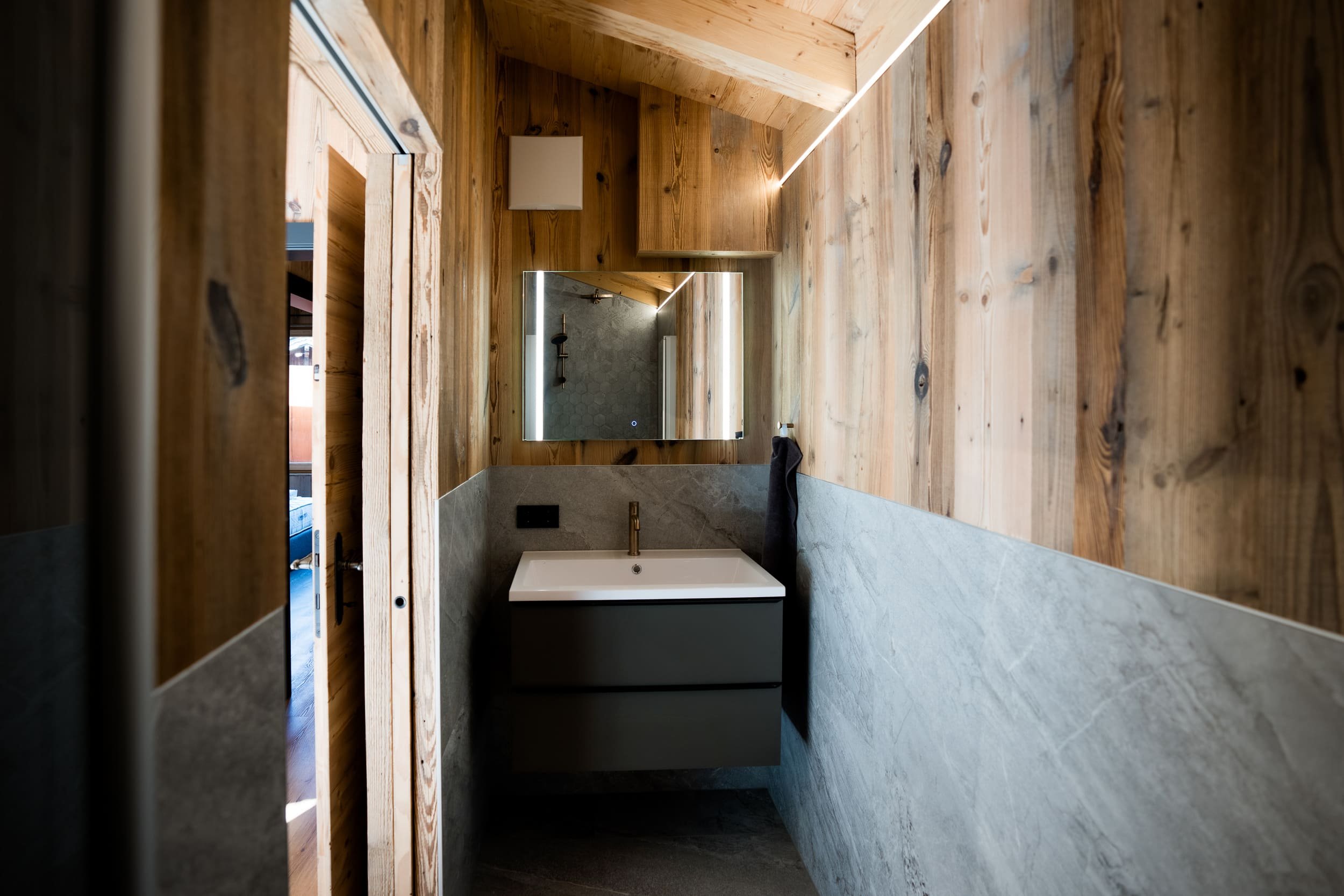 Ein Badezimmer mit Holzwänden, einem großen spiegel und einer modernen Waschbeckenanlage.
