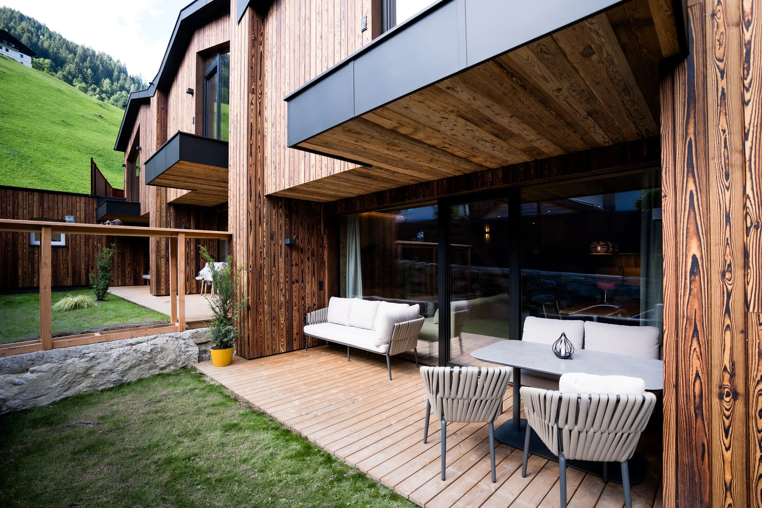 Außenansicht des SLØW Chalets mit privater Terrasse und Blick auf die Tiroler Berglandschaft.