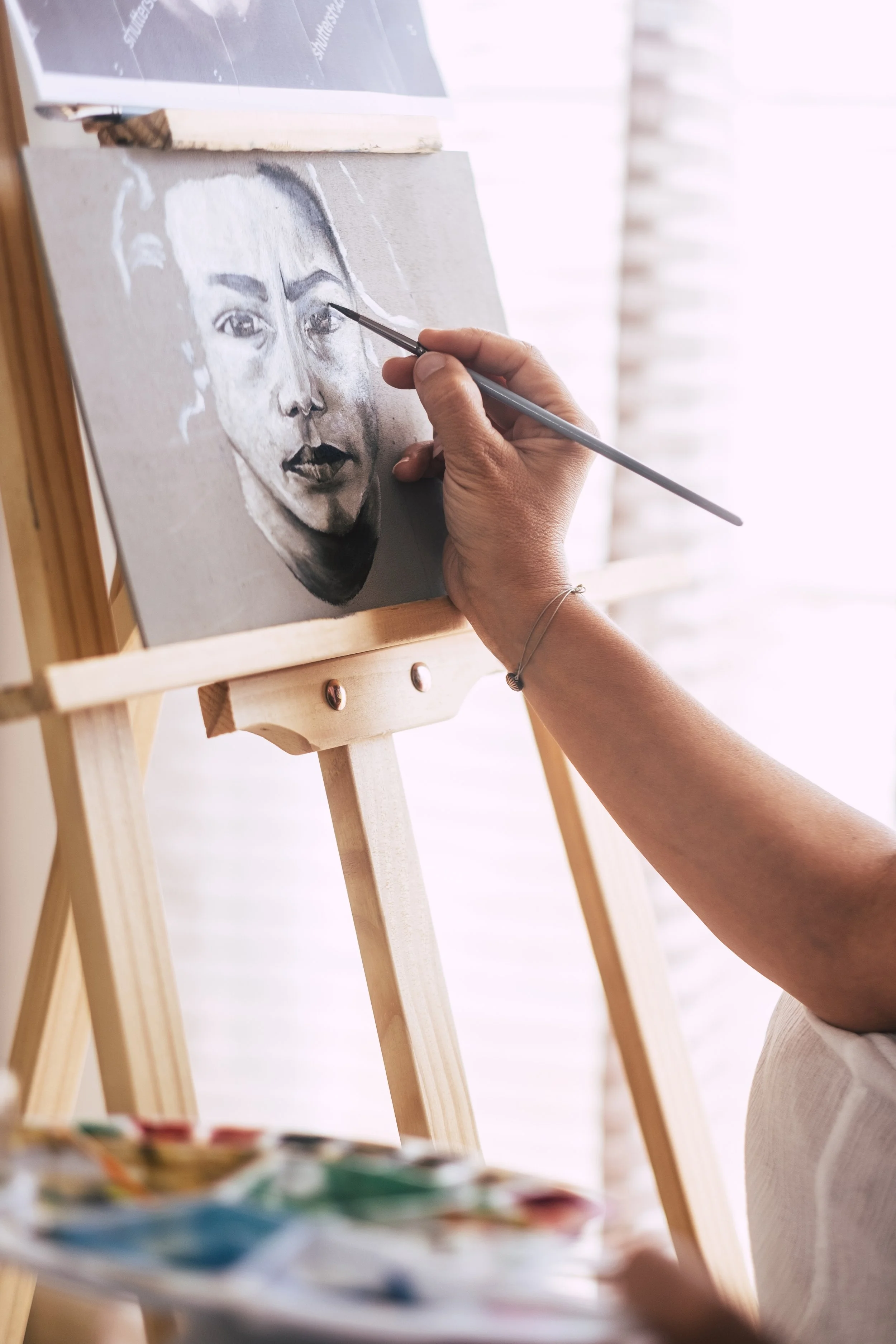 Künstlerin beim Malen eines Porträts auf einer Leinwand auf einem Holzständer