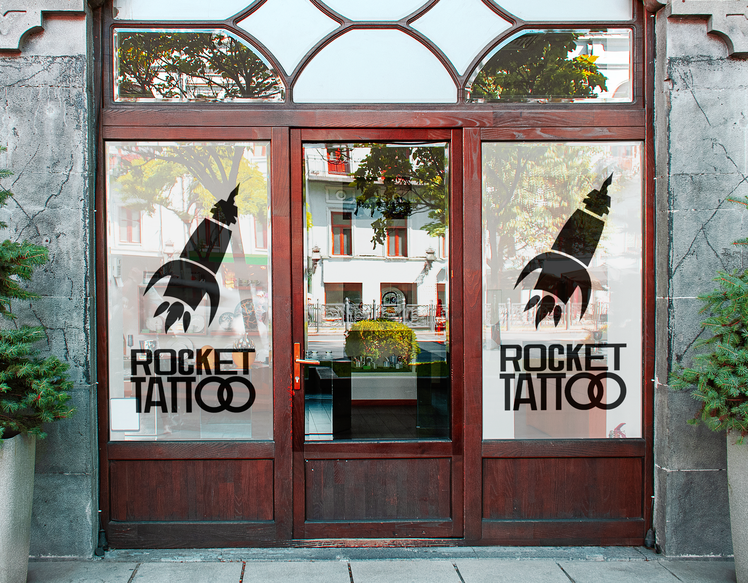 Vitrine d'un tatoueur nommé Rocket Tattoo, avec des logos de fusée stylisés sur les vitres.