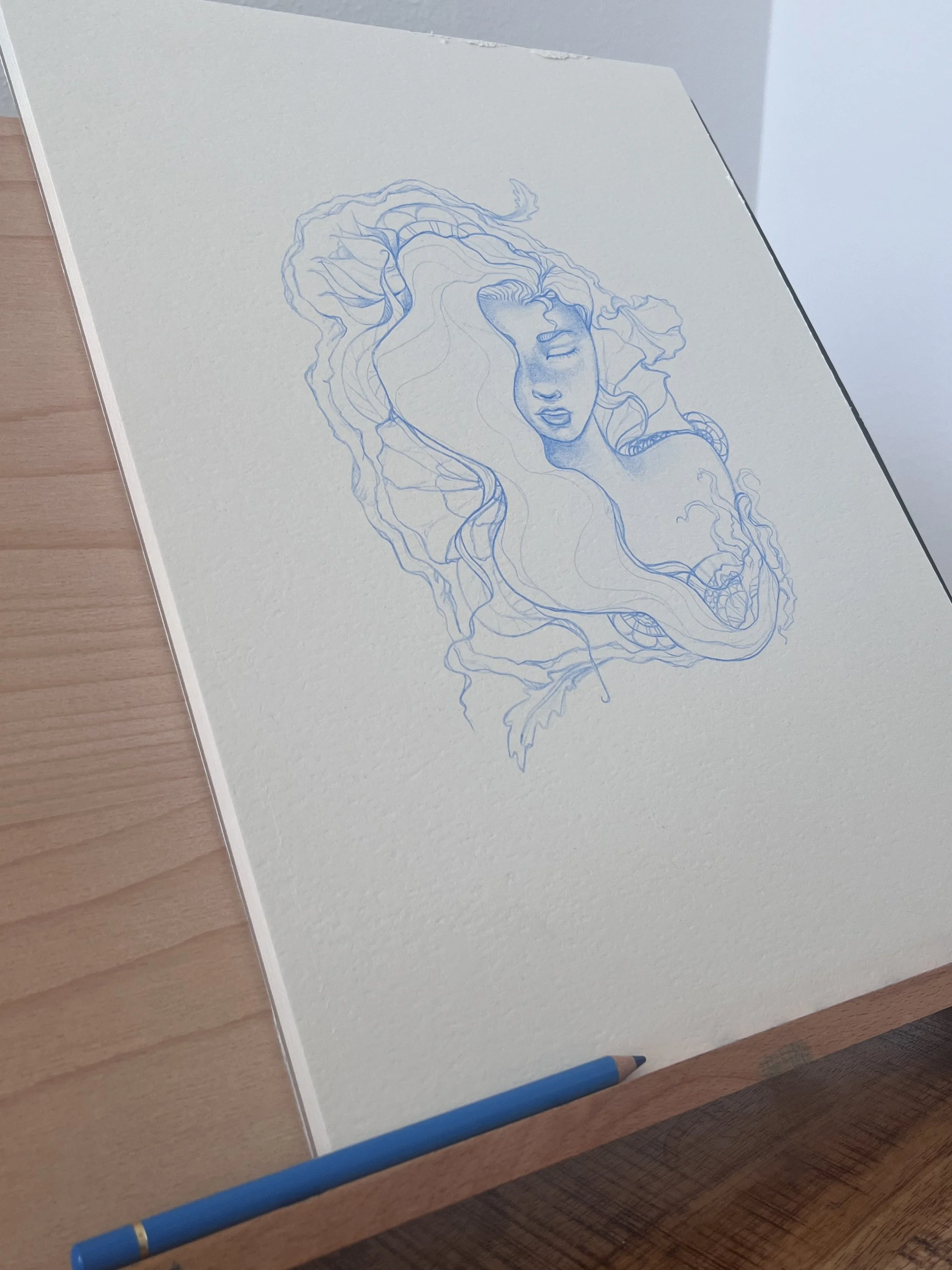 Skizze eines Mädchengesichts mit langen, fließenden Haaren auf Papier, liegt auf einem Holzschreibtisch, mit blauer Bleistift.