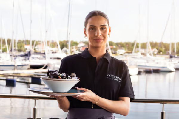 Bilde av servitør på Kystkroa som holder en tallerken med blåsjell på Kystkroa Bar og Restaurant