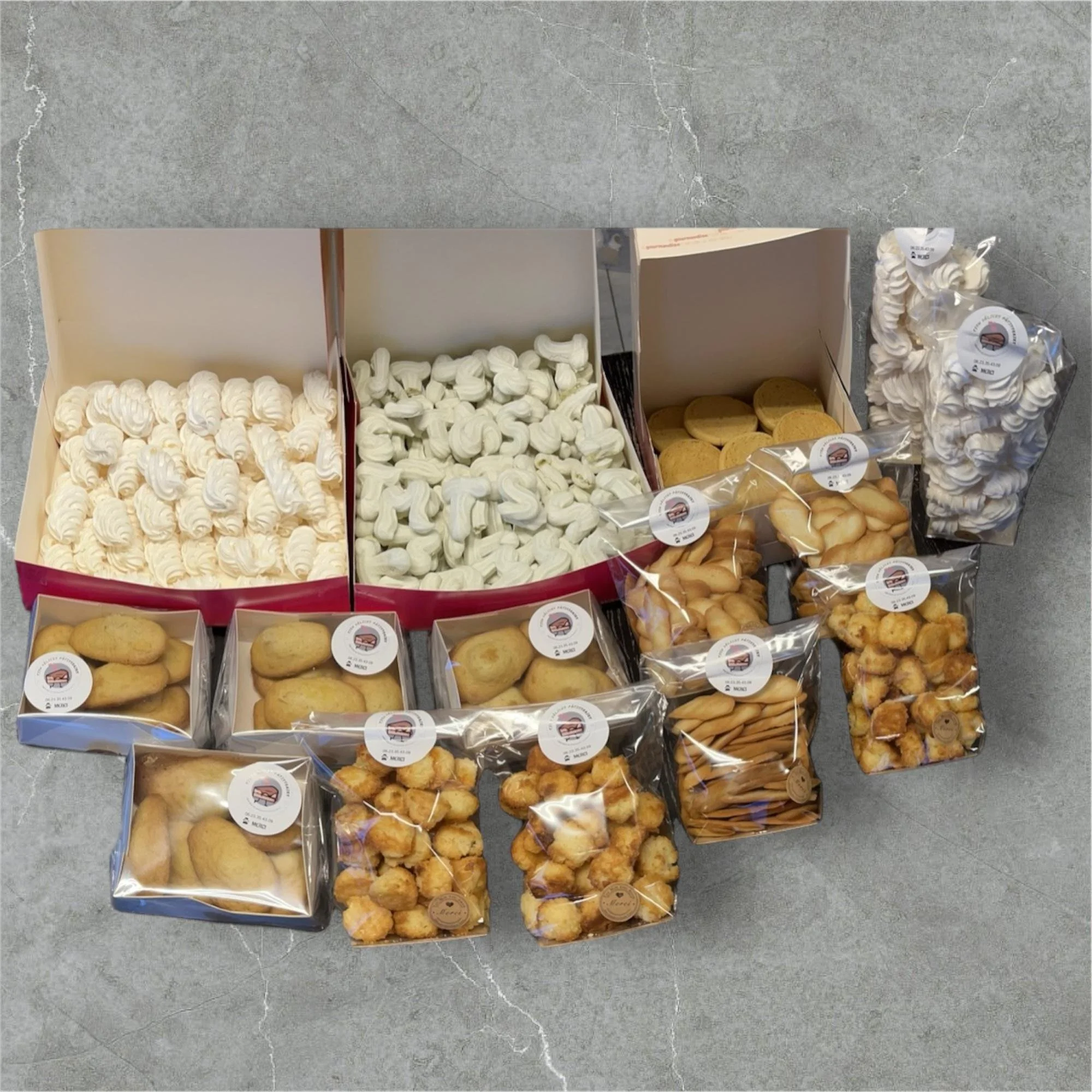 Various types of packaged cookies and meringues arranged on a gray surface.