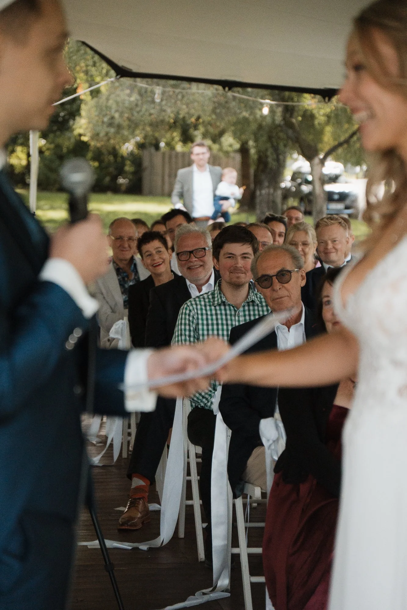 Bei einer Hochzeit tauschen sich der Bräutigam und die Braut während der Zeremonie aus, während die Gäste im Hintergrund Zuneigung zeigen und die Zeremonie beobachten.