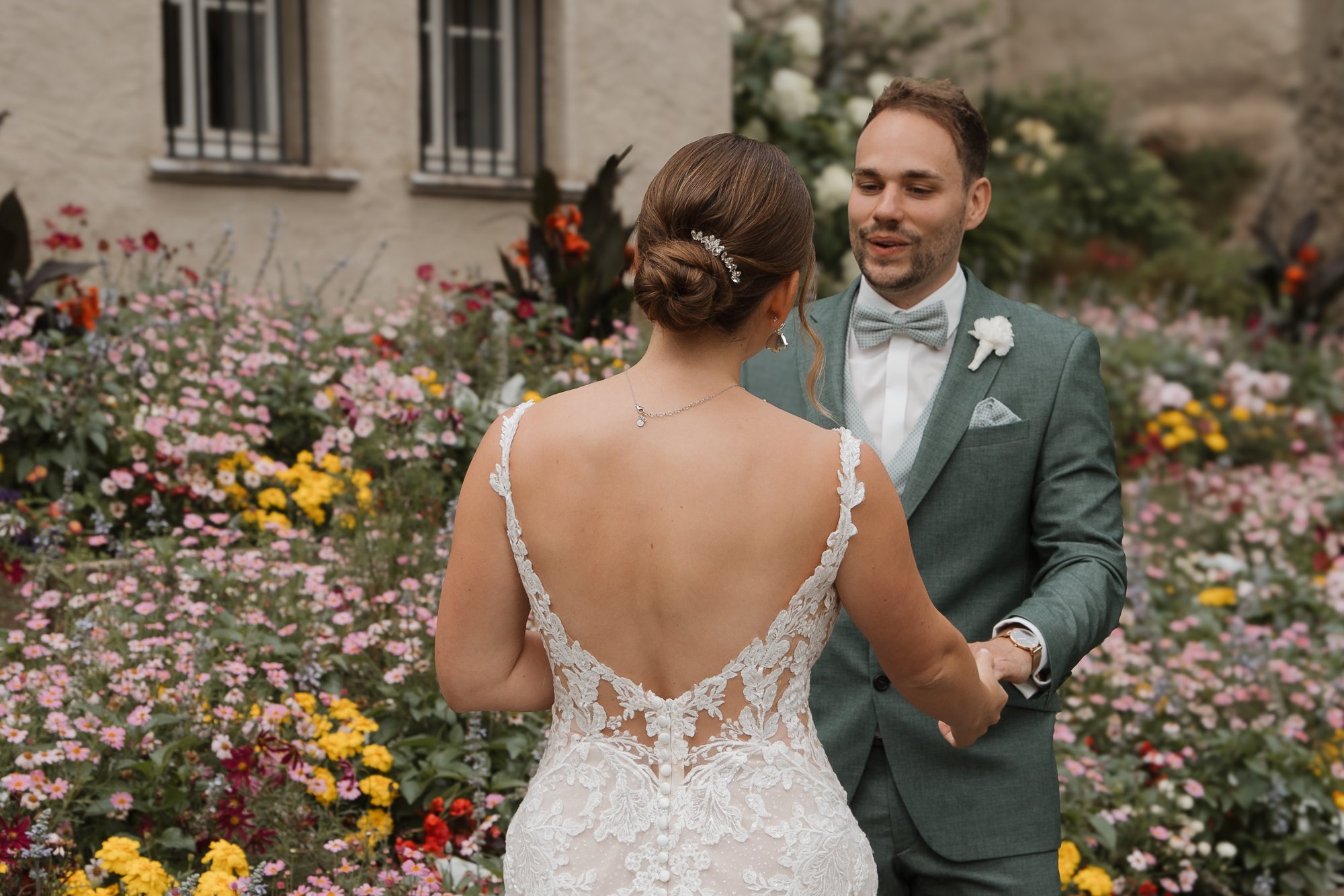 Ein brautpaar trägt sich bei einer Hochzeit im Garten, umgeben von bunten Blumen.