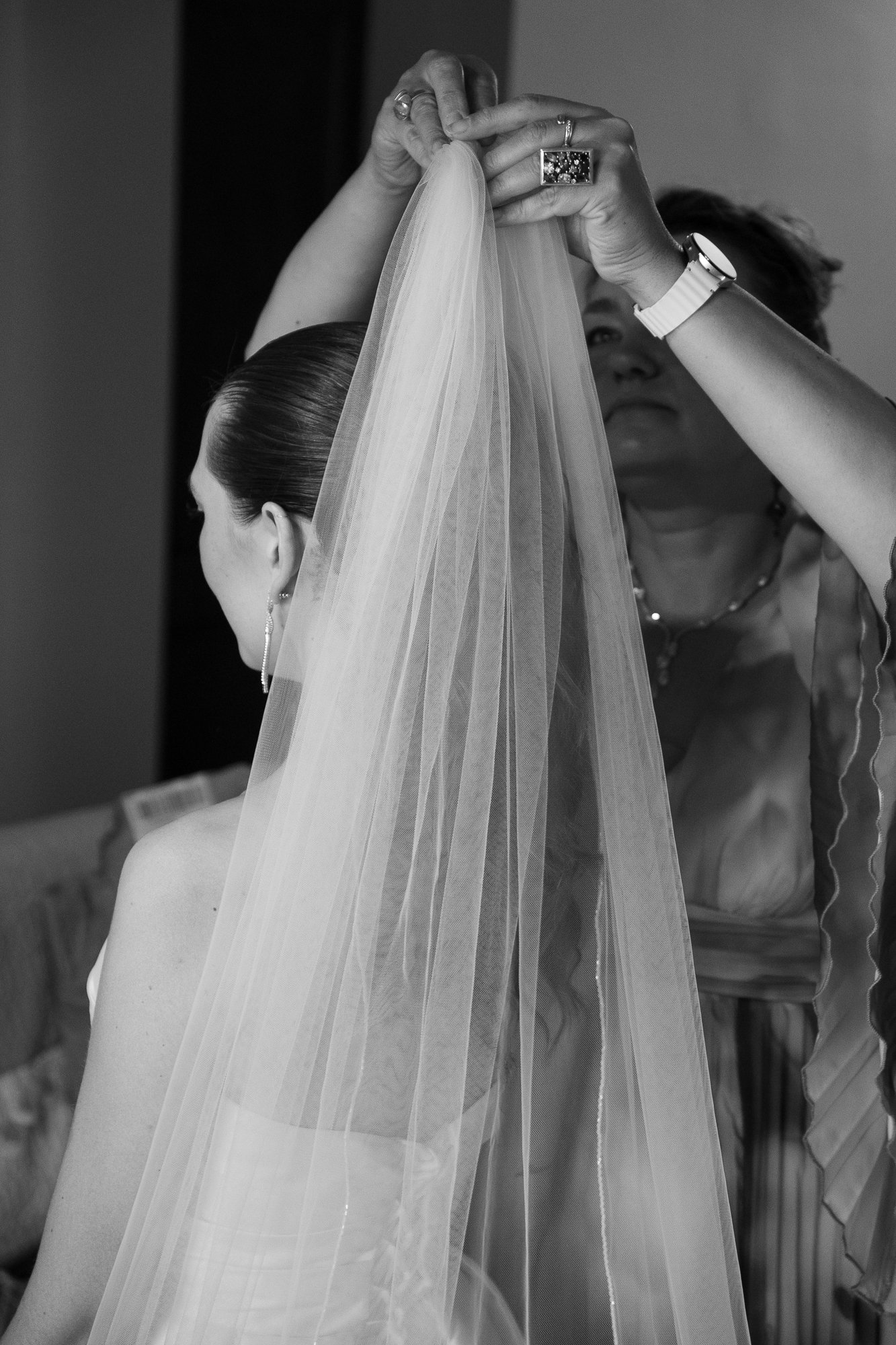 Eine Braut wird von einer Frau bei der Anbringung ihres Schleiers beraten, Schwarz-Weiß-Fotografie, Nahaufnahme.