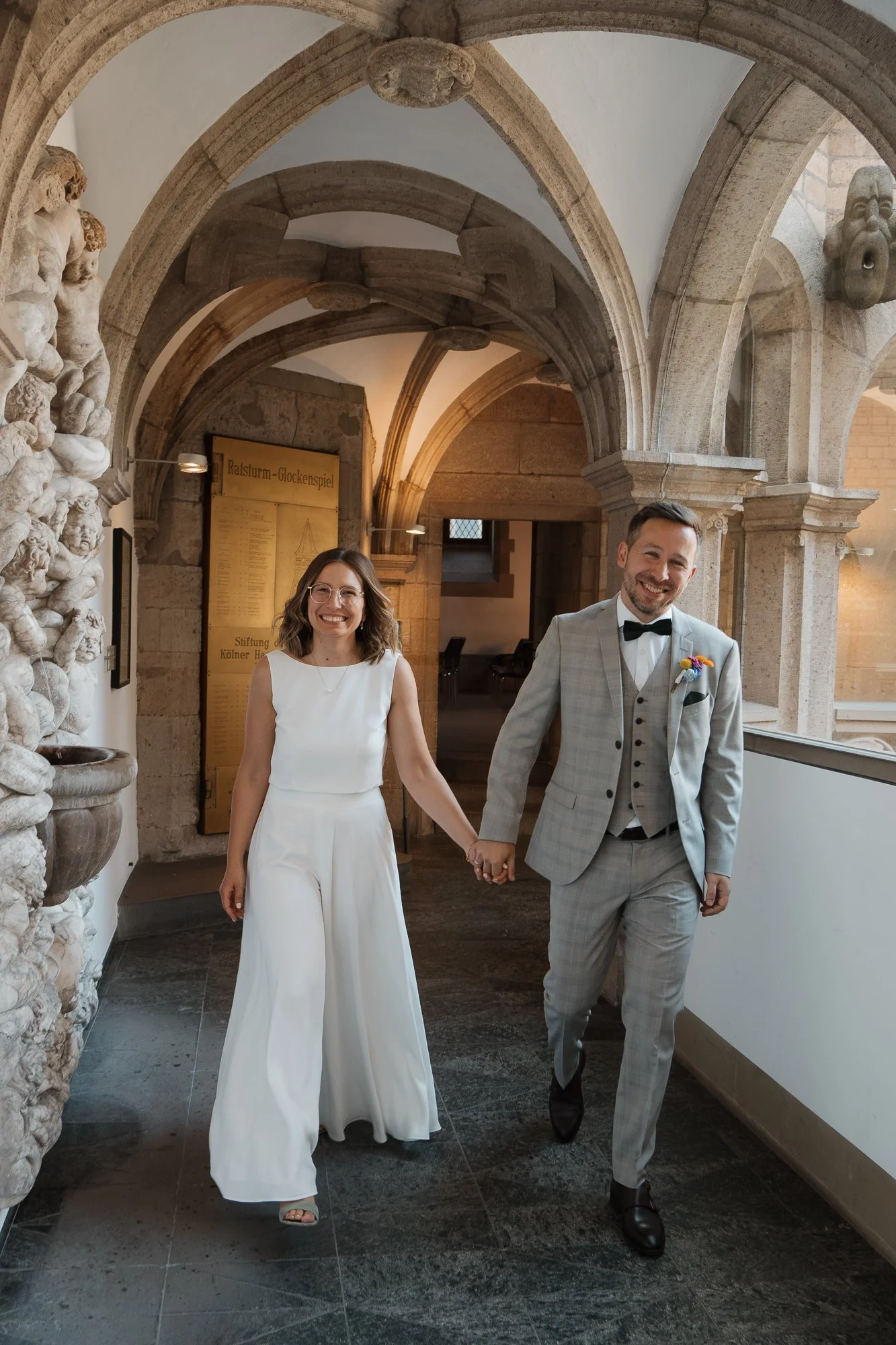 Ein glückliches Brautpaar, das an einer Hochzeit im historischen Gebäude frei Hand hält.
